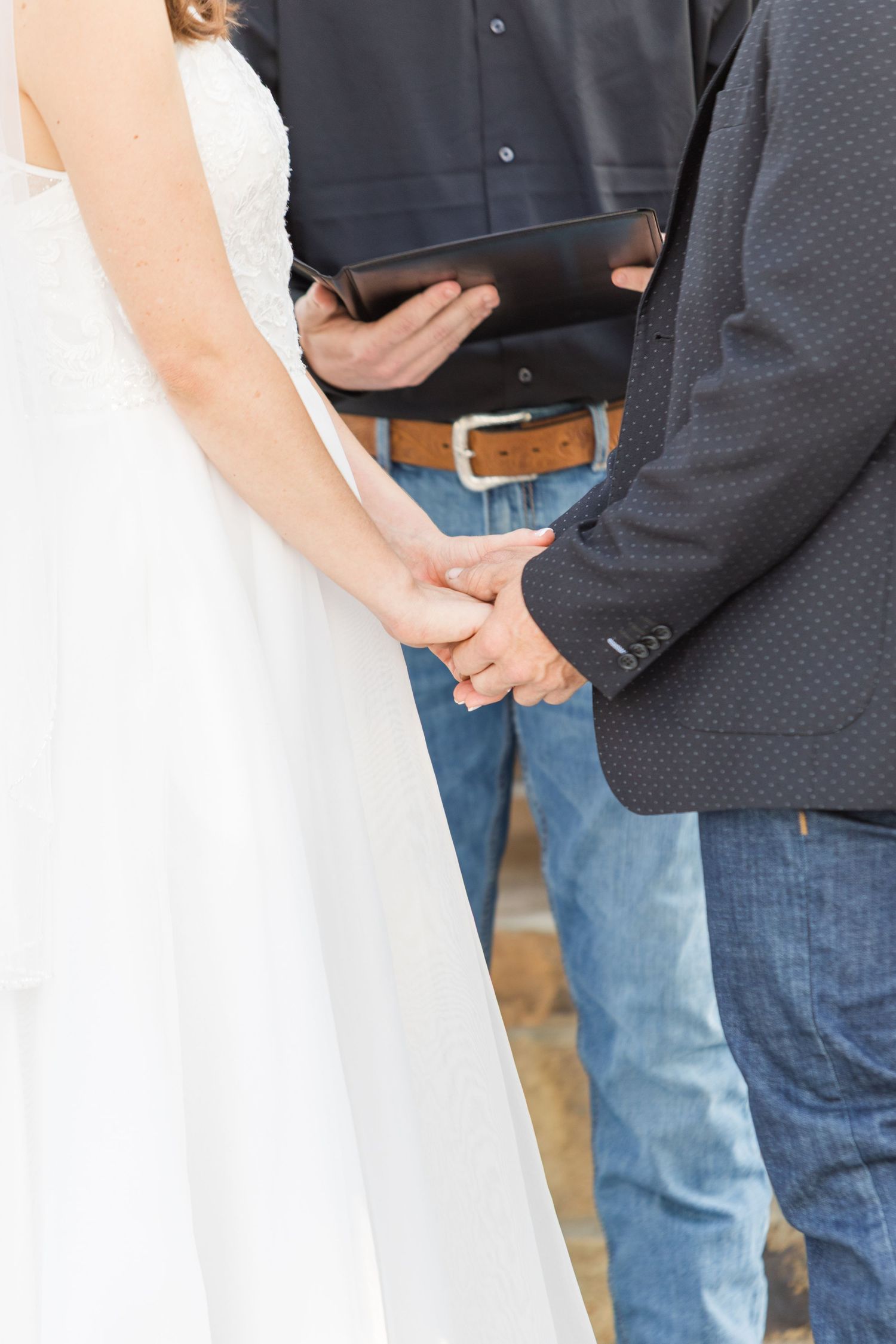 Close-up of wedding rings being exchanged during an outdoor ceremony.
