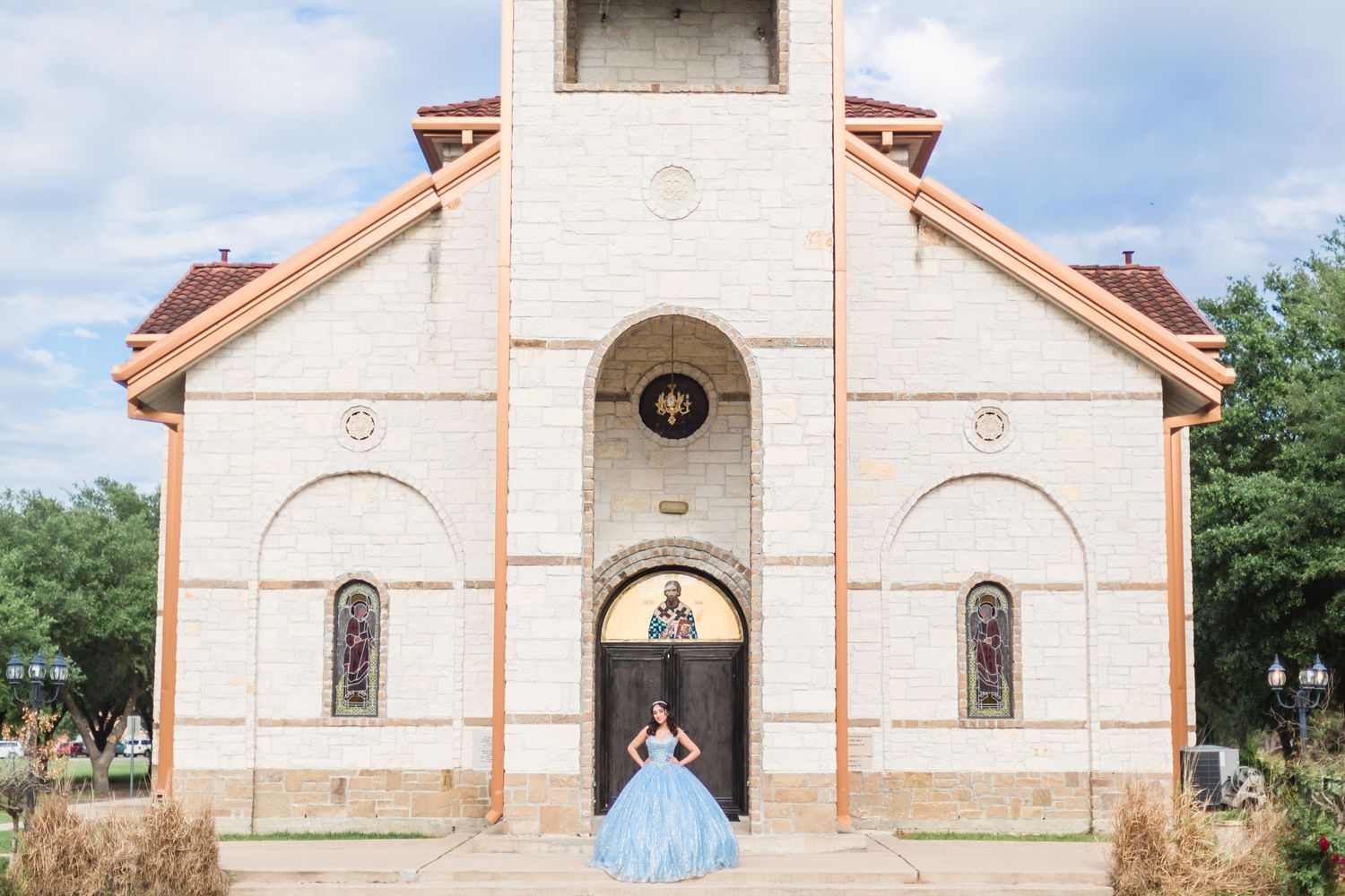 White stone church with terracotta trim and arched doorway photographed from different angles.