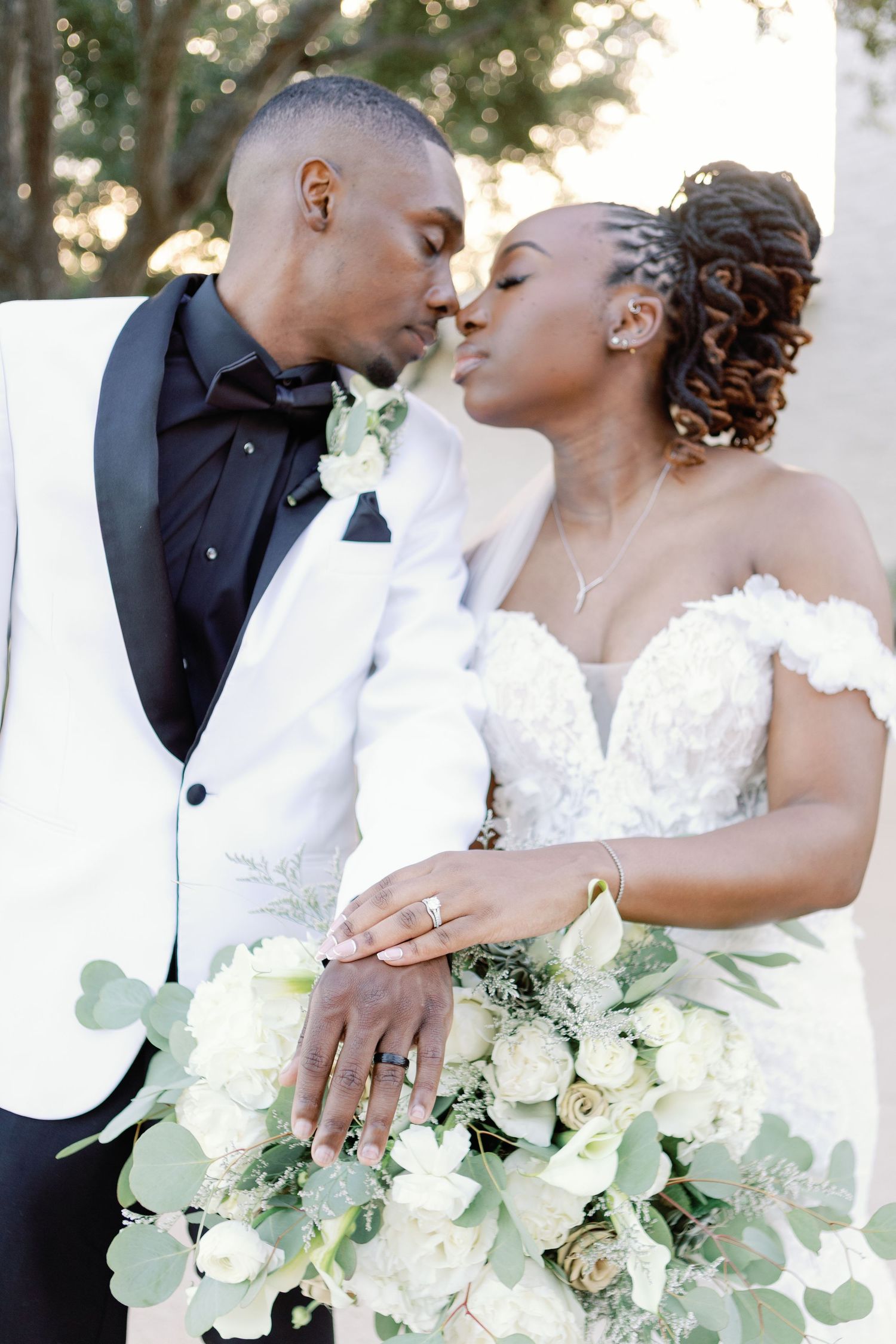 Romantic wedding photography captures intimate moments between newlyweds with elegant white floral bouquet details.