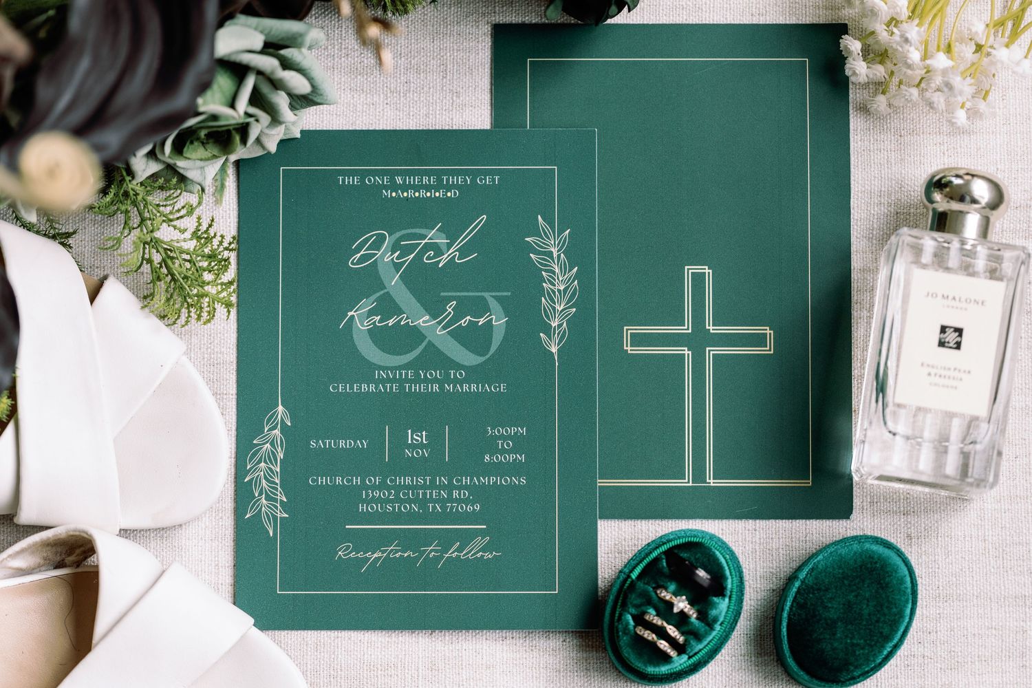Elegant dark green wedding invitation suite with white calligraphy and floral accents laid out on a white surface.