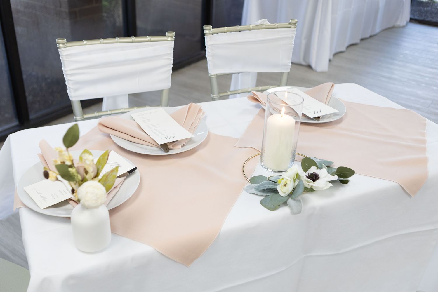 Elegant table setting with blush linens and floral centerpieces.