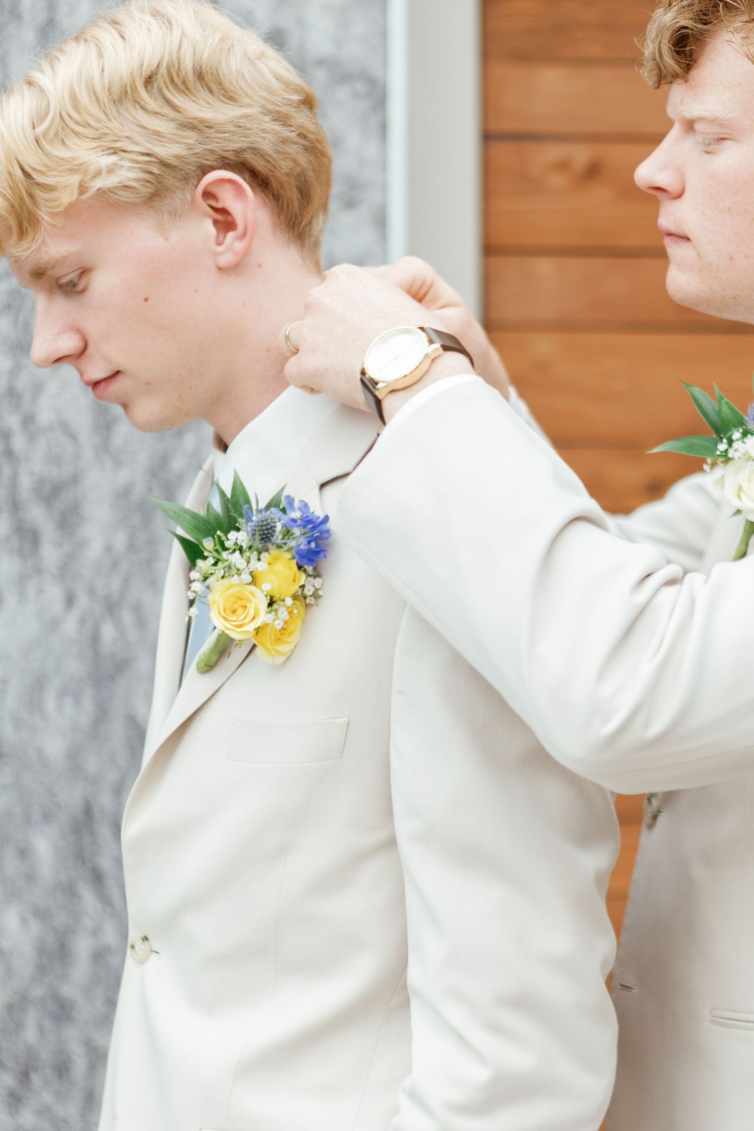 Side profile view of person in cream colored suit preparing for wedding ceremony.