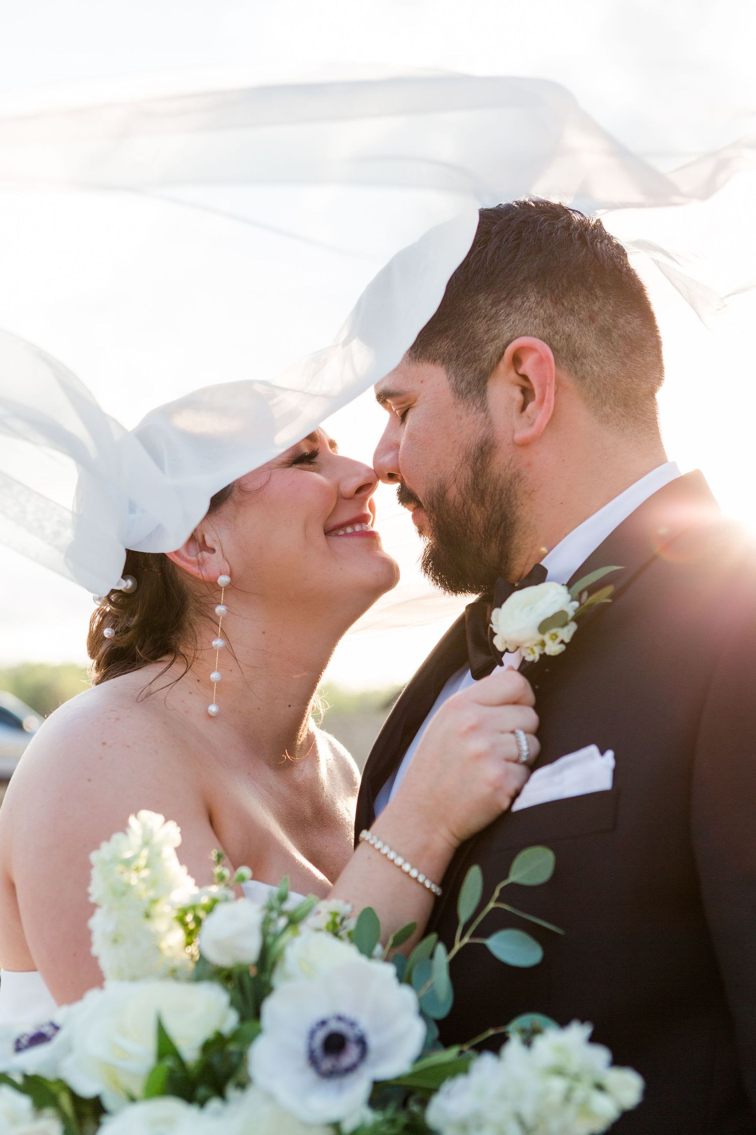 Sunlit wedding portrait with white anemone bouquet and intimate poses.