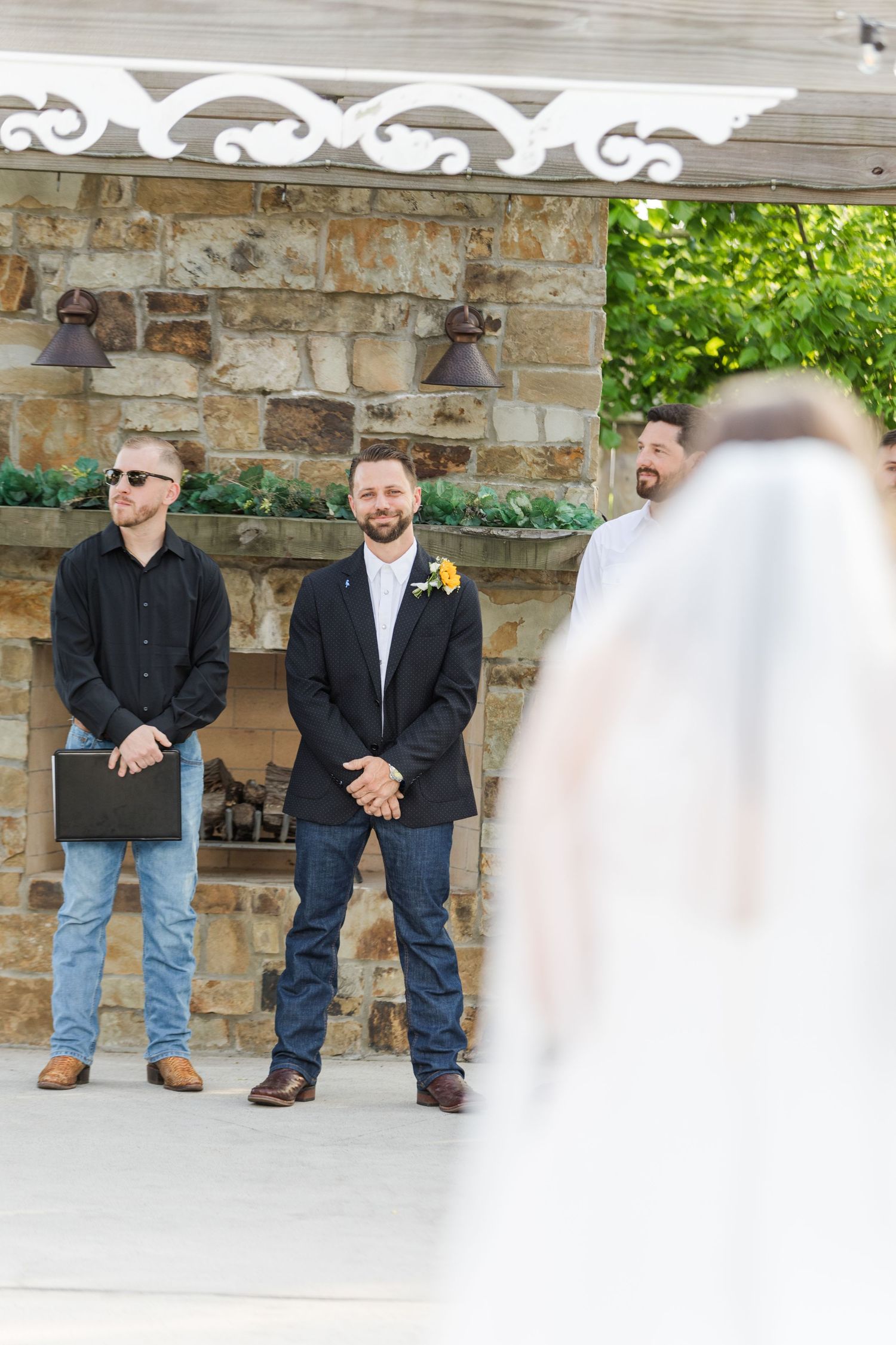 Wedding party lineup under decorative stone archway.