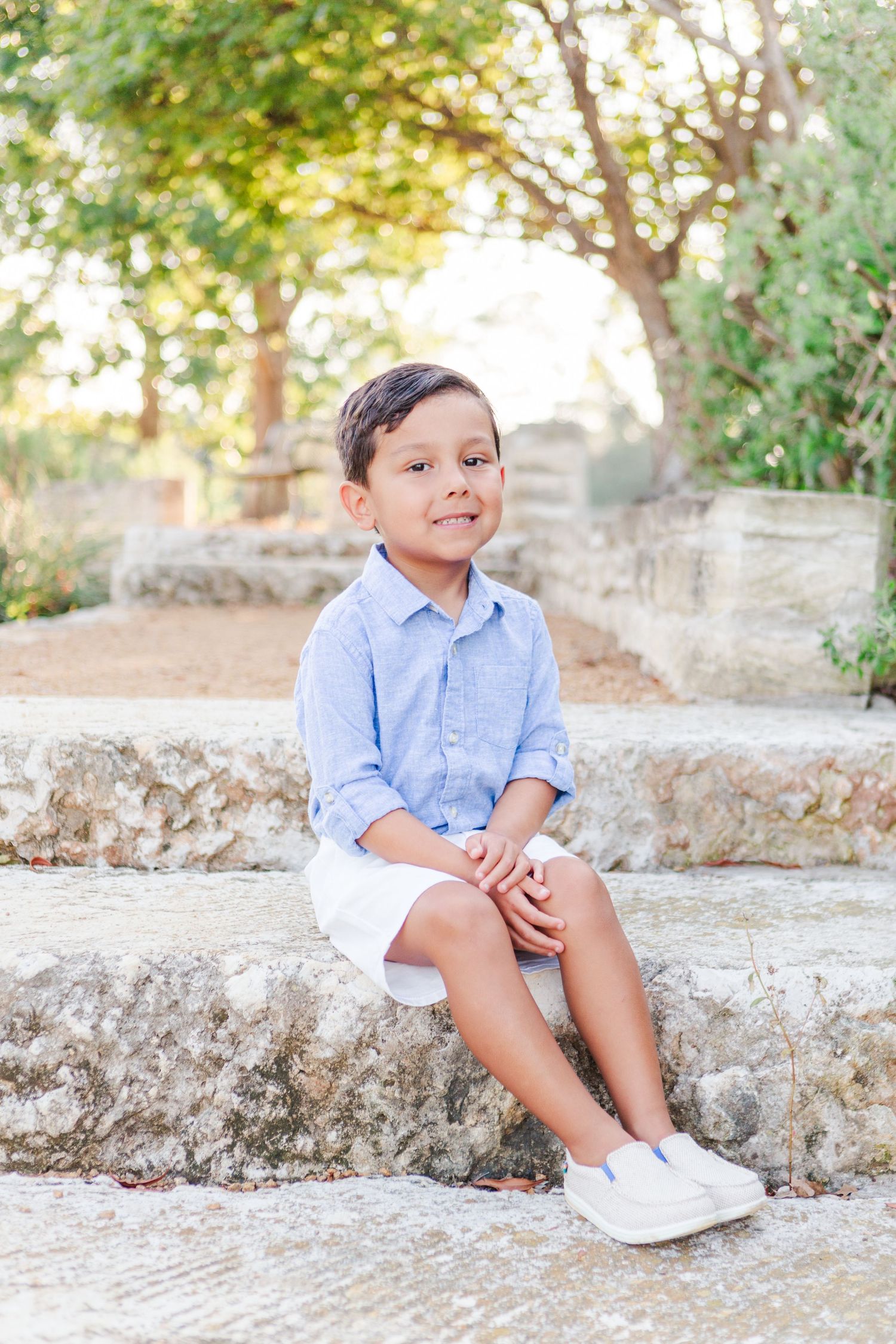 Series of casual portraits of child sitting on stone steps in blue shirt and white sneakers.