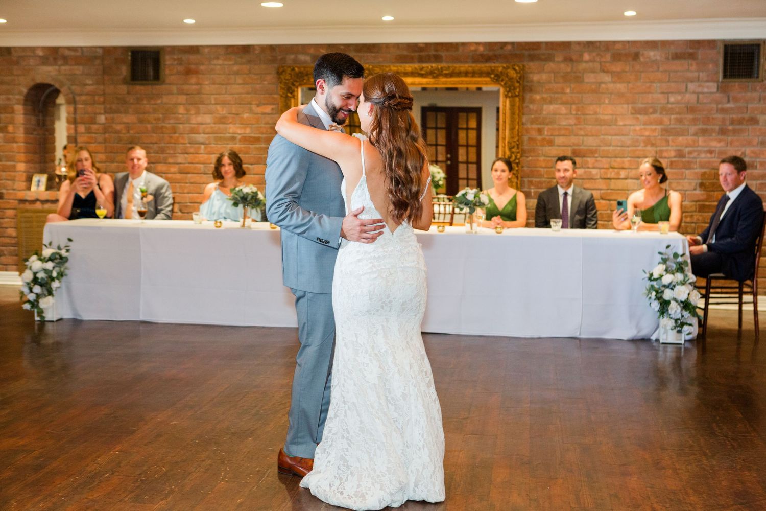 Elegant wedding reception venue with exposed brick walls and white floral decorations.