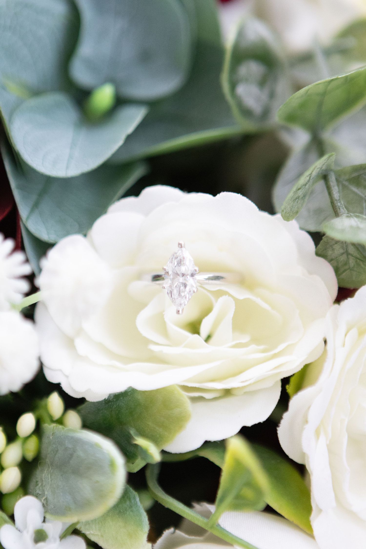 Elegant white roses and silver rings arranged with sage green eucalyptus leaves.