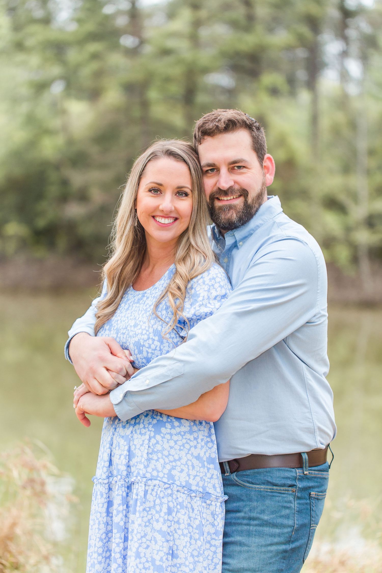 A couple embraces in a wooded area wearing coordinating blue outfits.