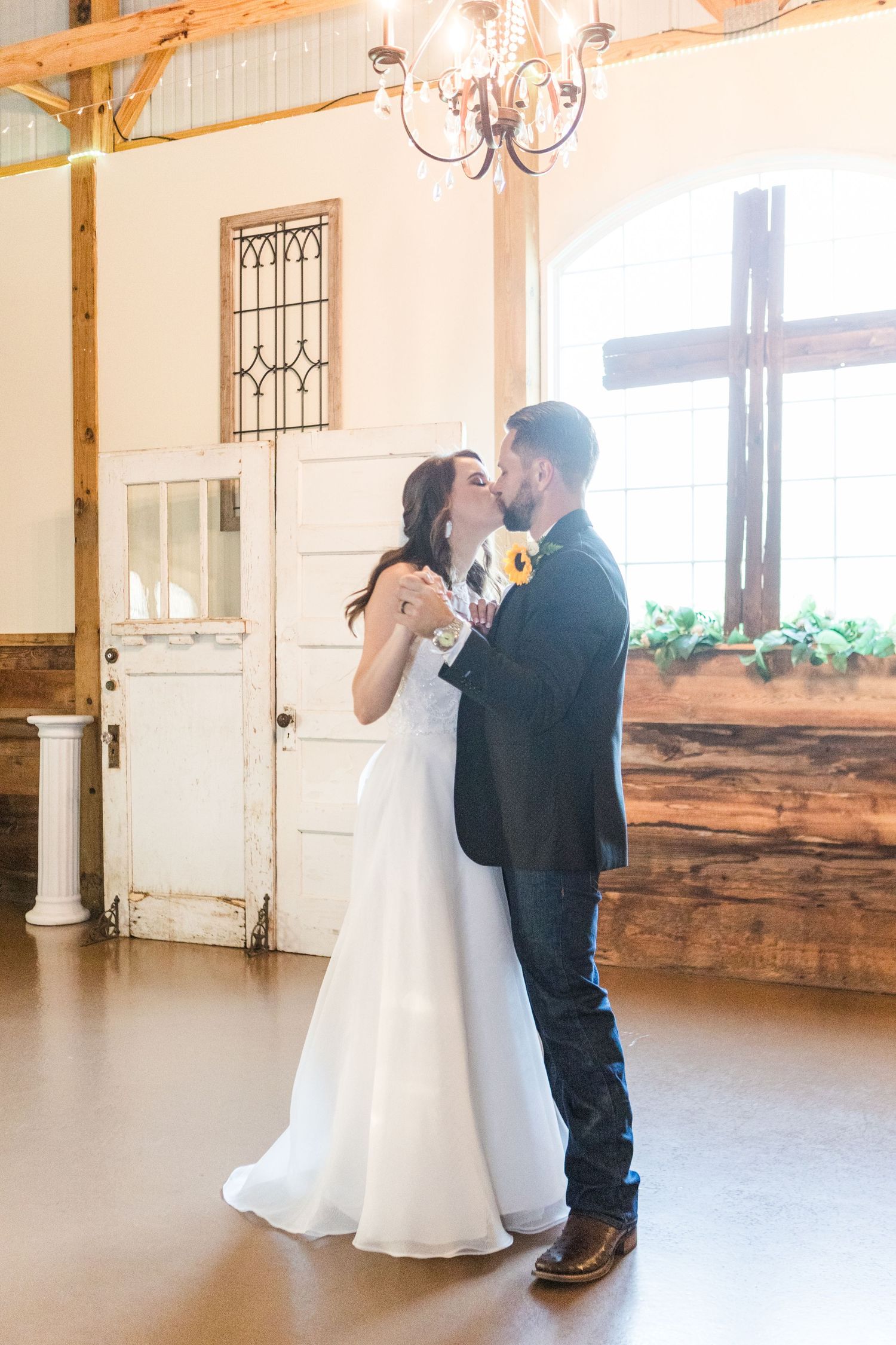 Couple sharing a romantic dance moment in a rustic indoor venue with warm lighting.