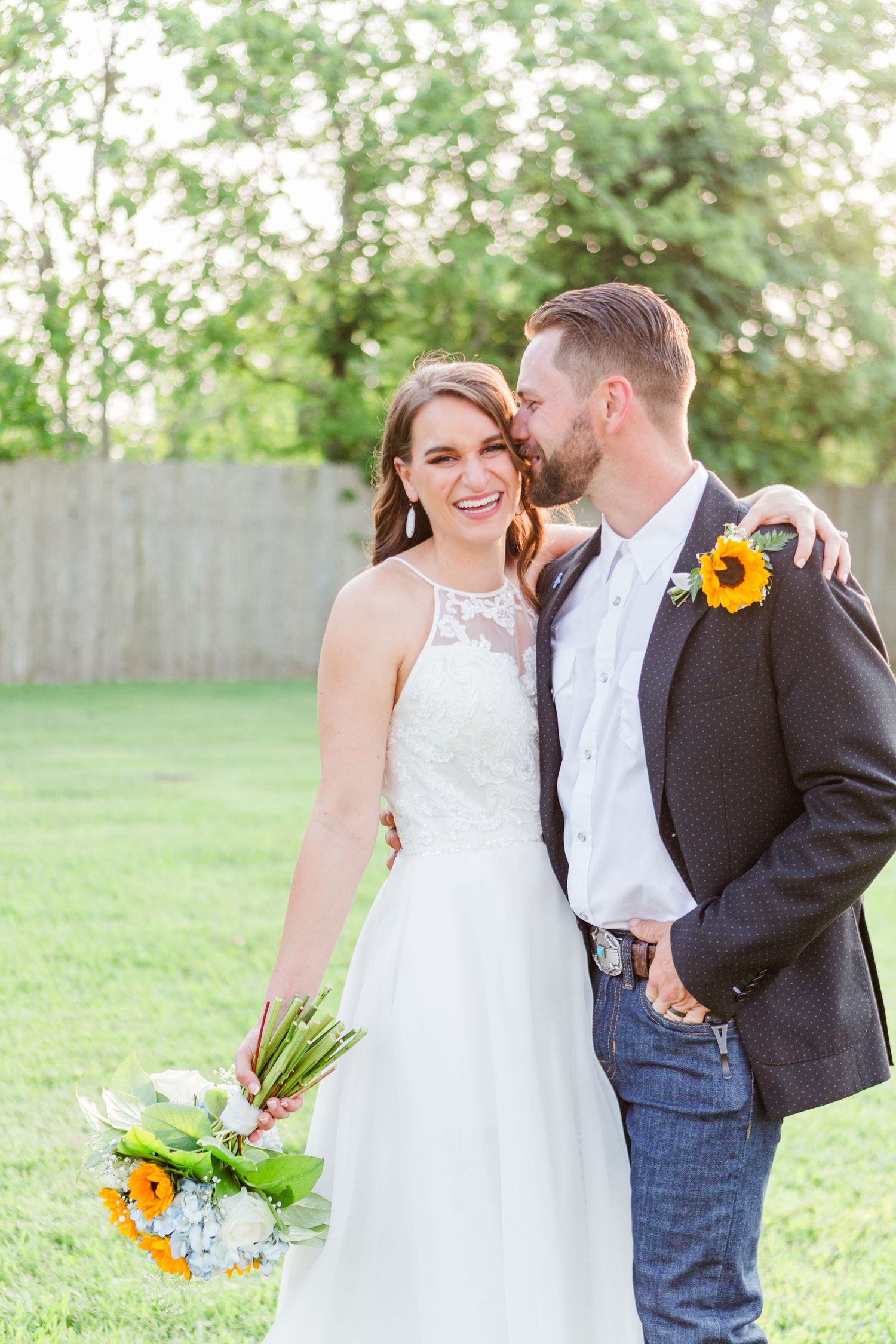 Wedding couple embracing in garden setting with sunflower bouquet.