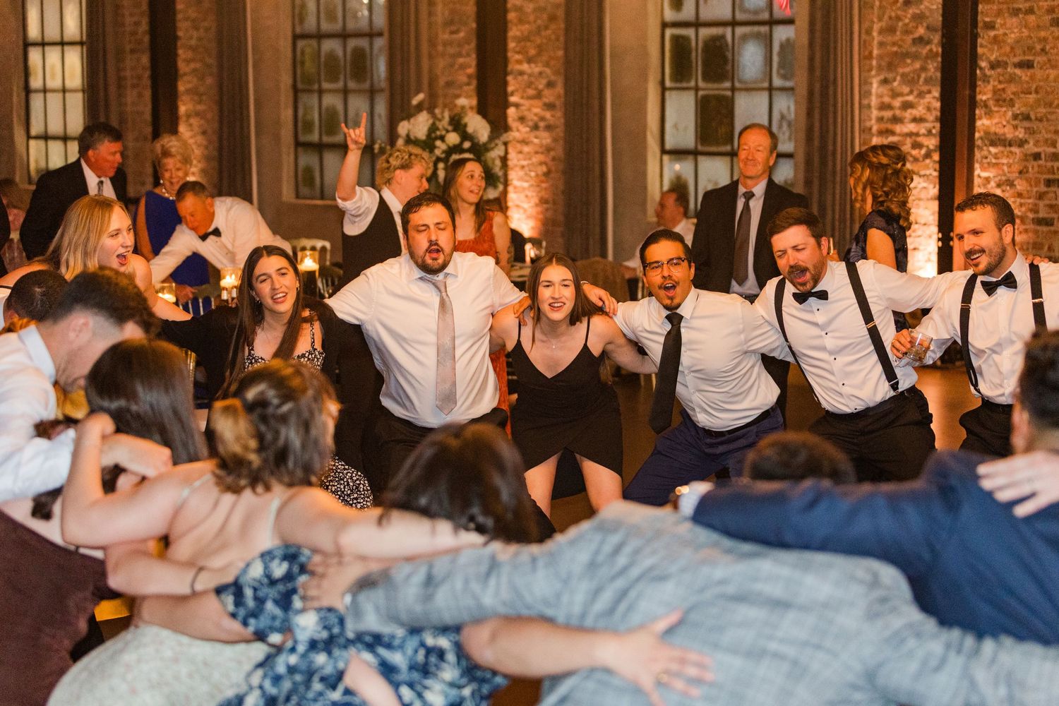 Wedding celebration at rustic venue with brick walls and elegant chandelier lighting.