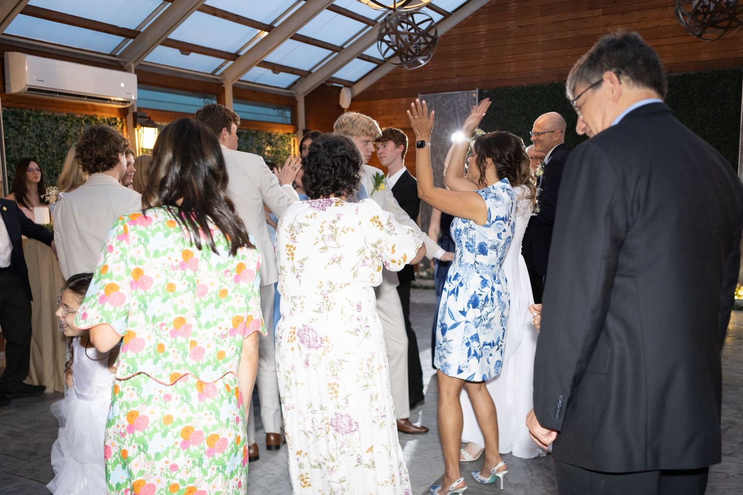 Wedding celebration with guests dancing and mingling in a rustic indoor venue.