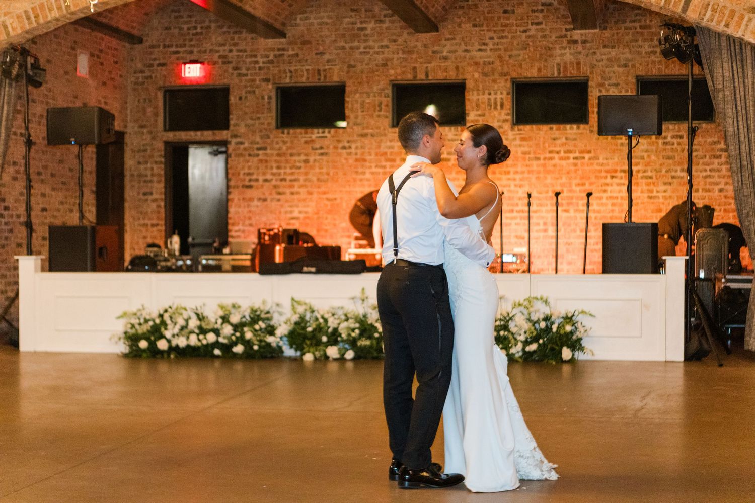 Elegant wedding venue features exposed brick walls and rustic wood beam ceiling.