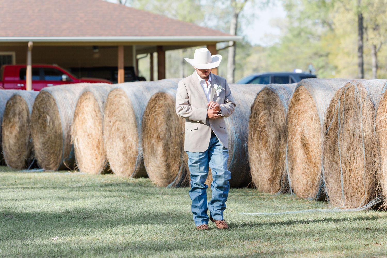 Round hay bales dot the countryside at a rustic outdoor wedding venue.