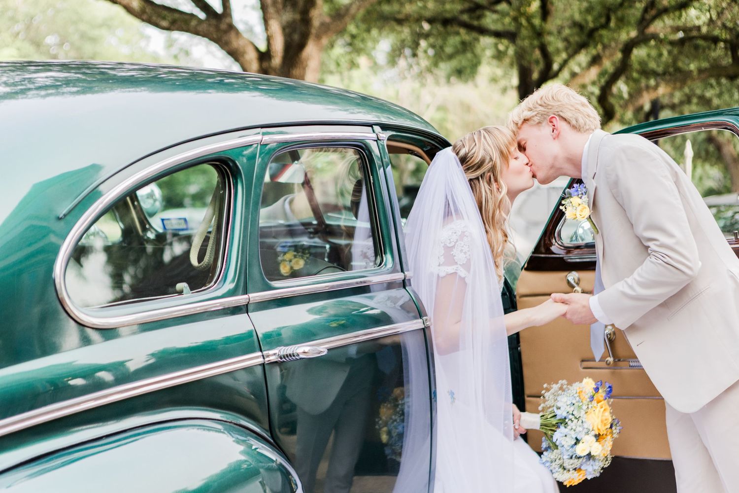 Wedding photoshoot featuring couple and vintage green car in garden setting.