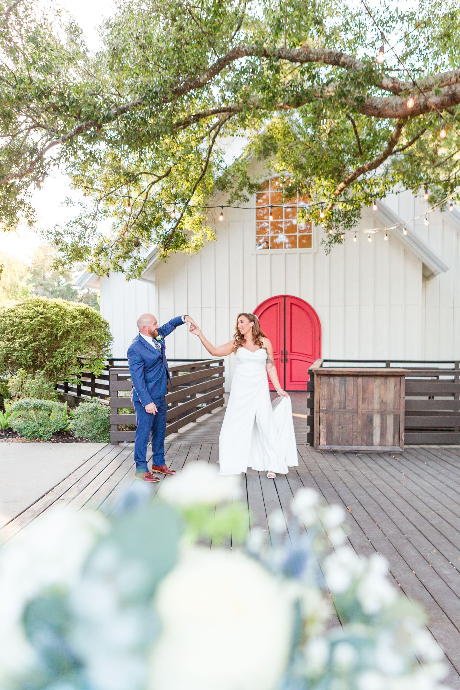 Romantic outdoor wedding photoshoot on a wooden deck with elegant white dress and blue suit.