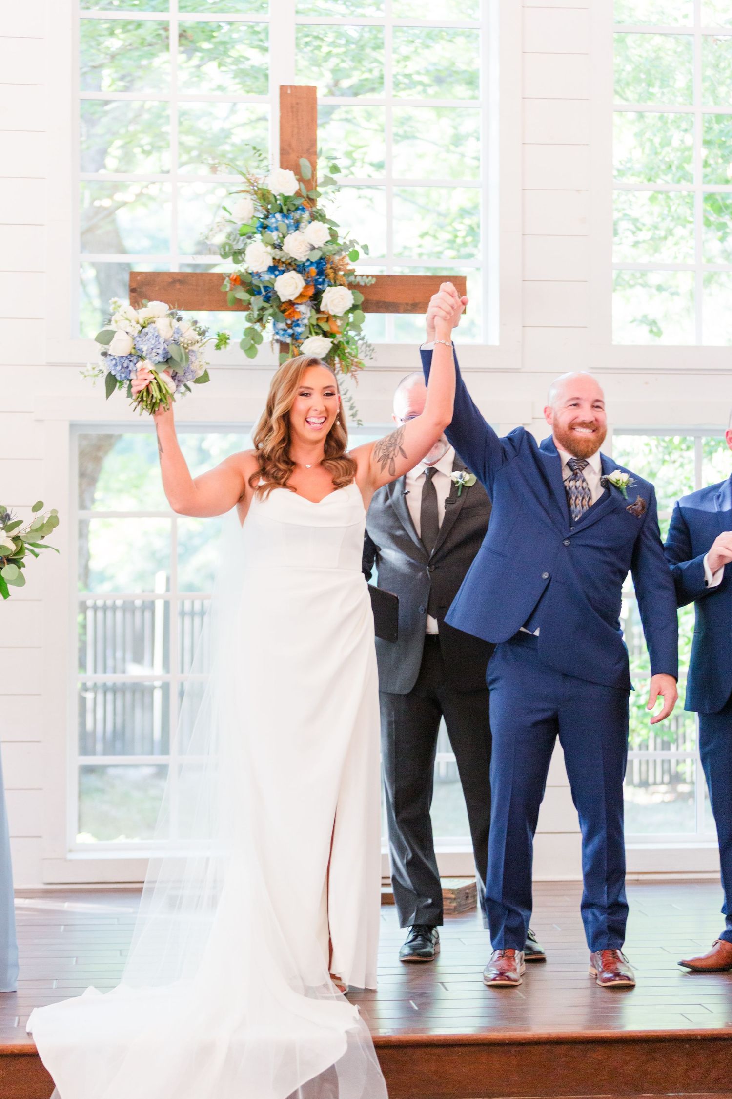 Newlyweds celebrating joyfully after their ceremony in a sunlit venue with white pillars.