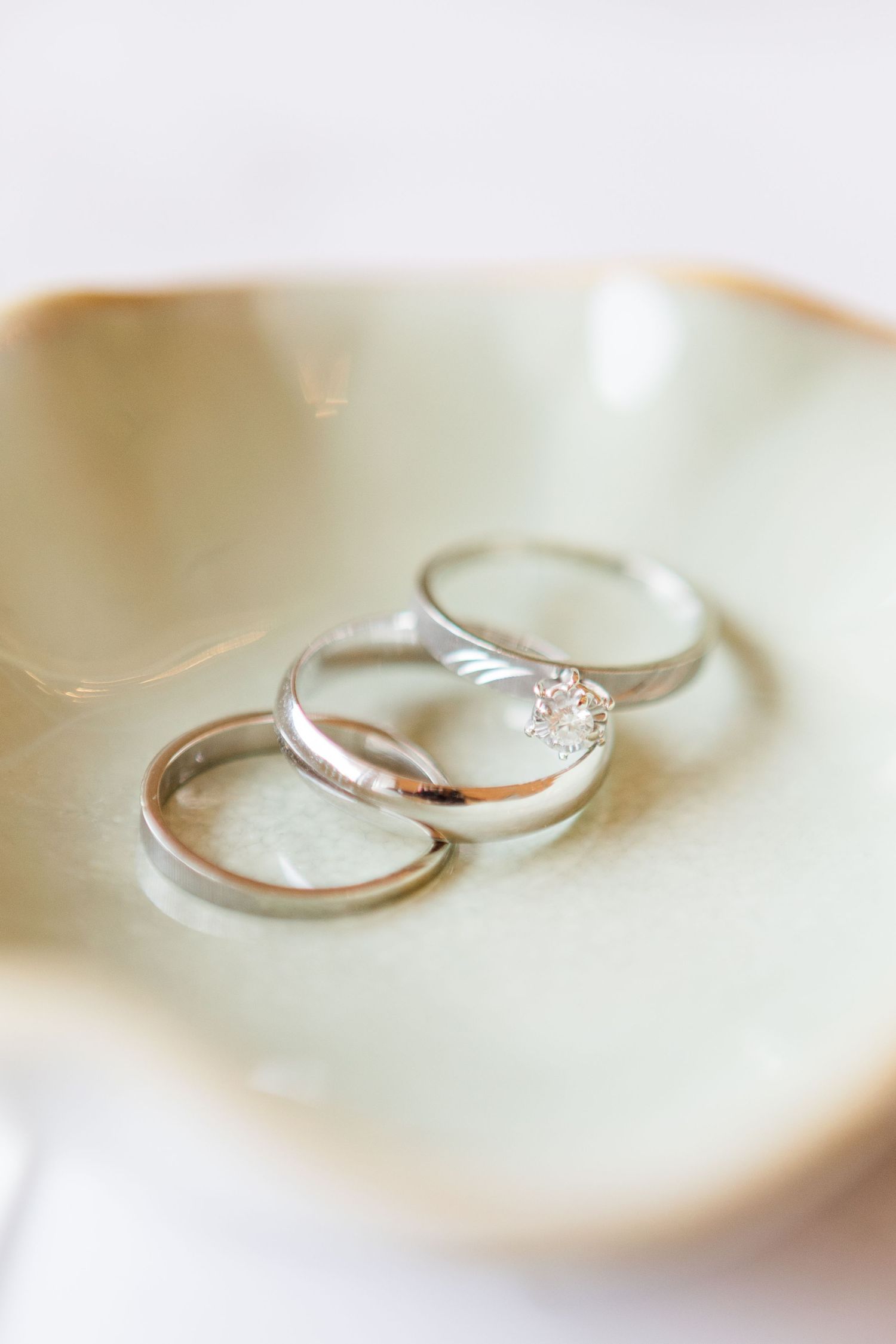 Wedding rings photographed in soft focus on a light surface.