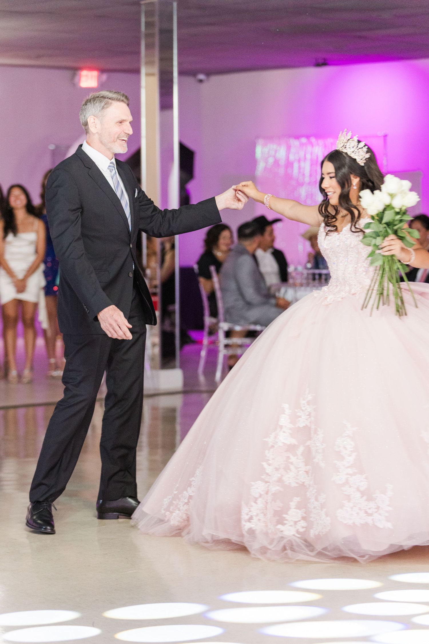 Elegant dance moment captured during a special celebration in a purple-lit venue with a flowing pink gown.