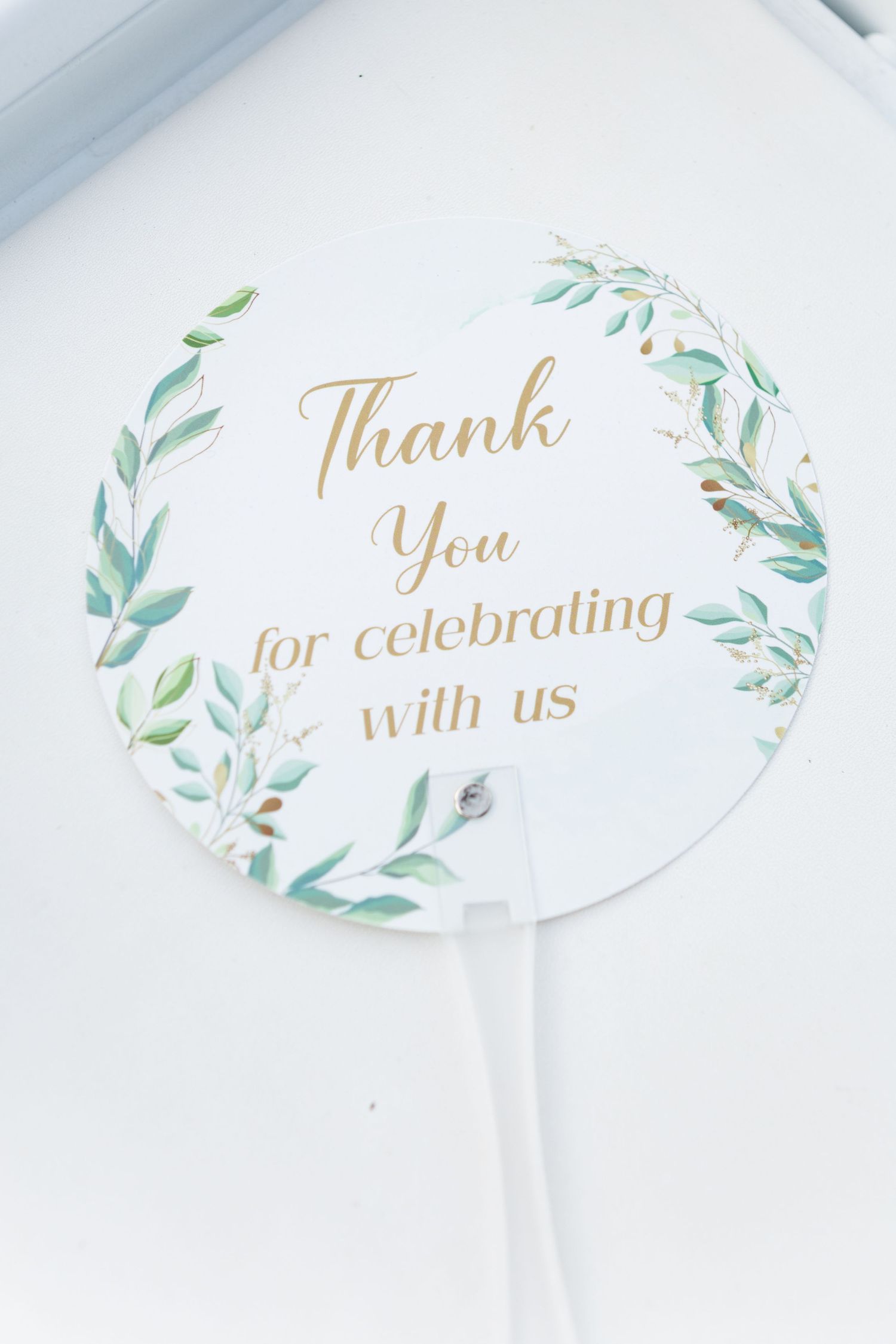 Elegant white thank you card with gold lettering and watercolor greenery design showing text 'Thank you for celebrating with us'.