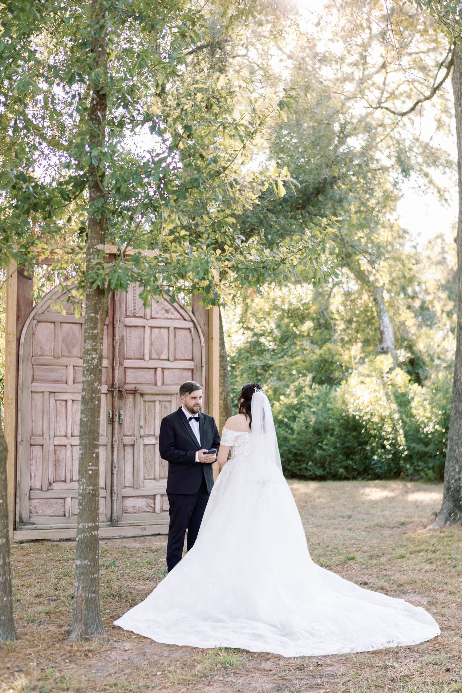 Romantic first look moment at outdoor wedding venue with rustic wooden doors.
