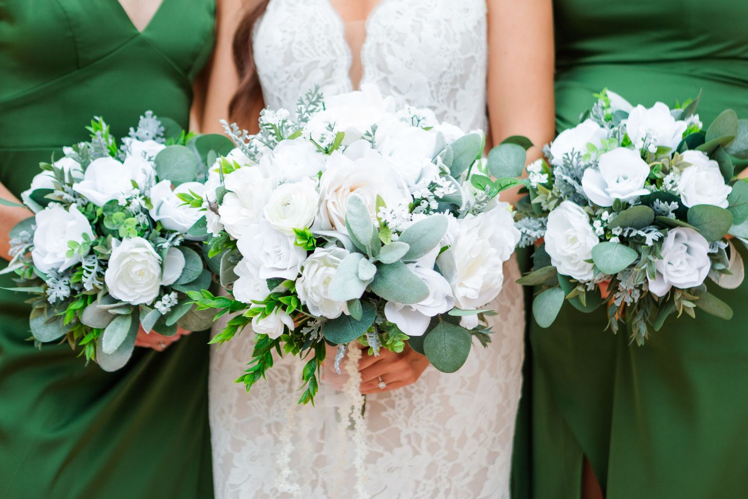 Elegant white floral wedding bouquets arranged in a row with green accents.
