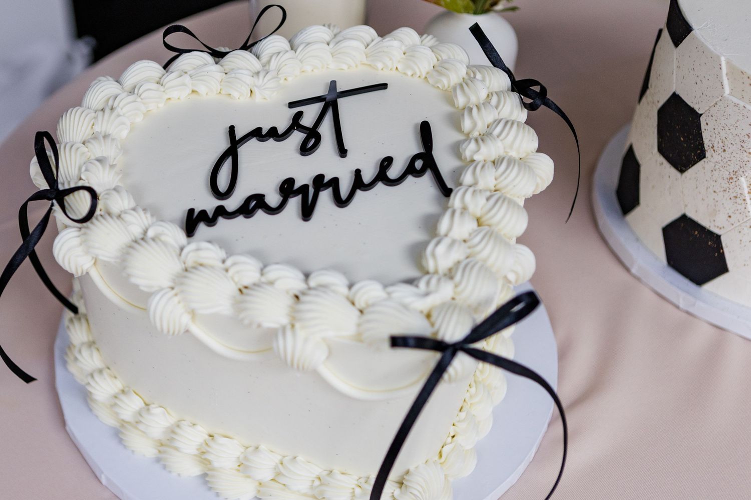 Wedding cake decorated with white frosting and delicate black ribbon details.