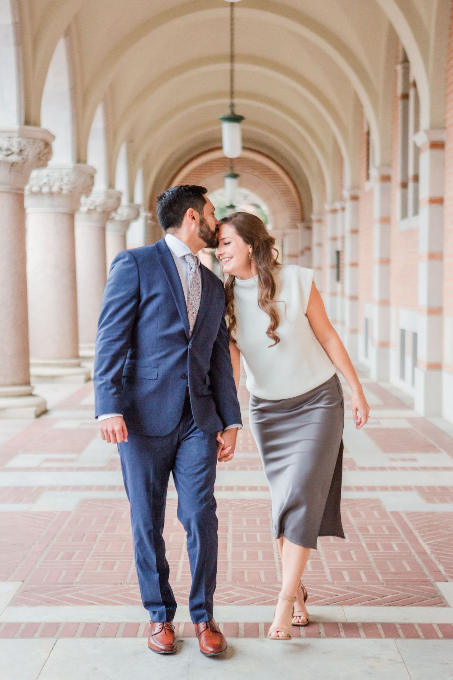 Couple shares romantic pose in beautiful columned corridor.