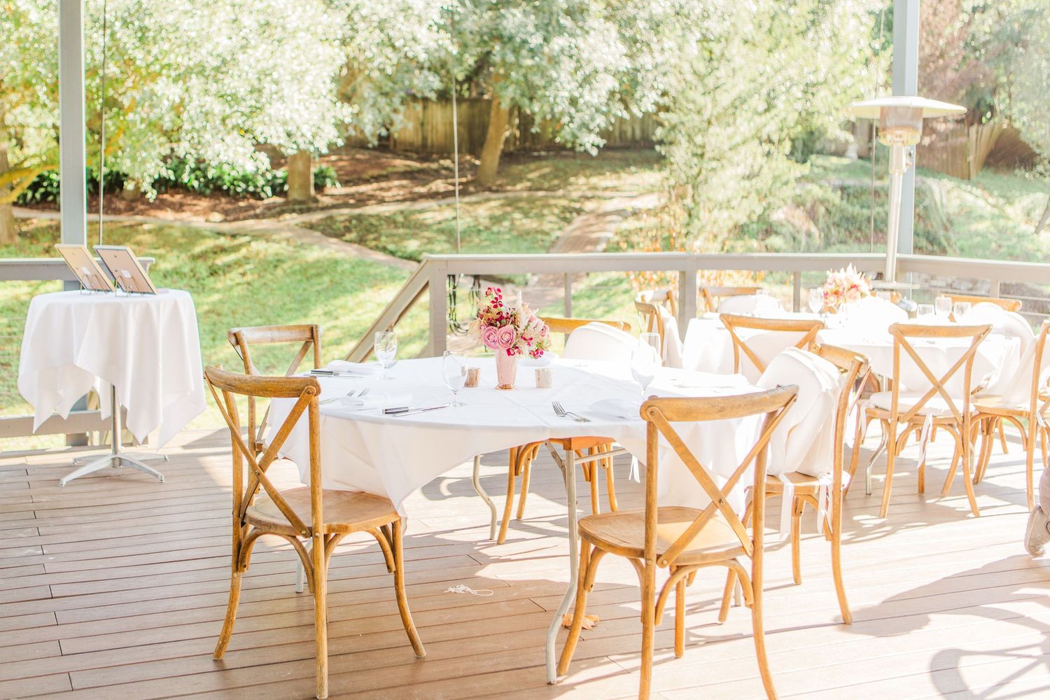 Rustic wooden crossback chairs arranged at an outdoor wedding reception venue.