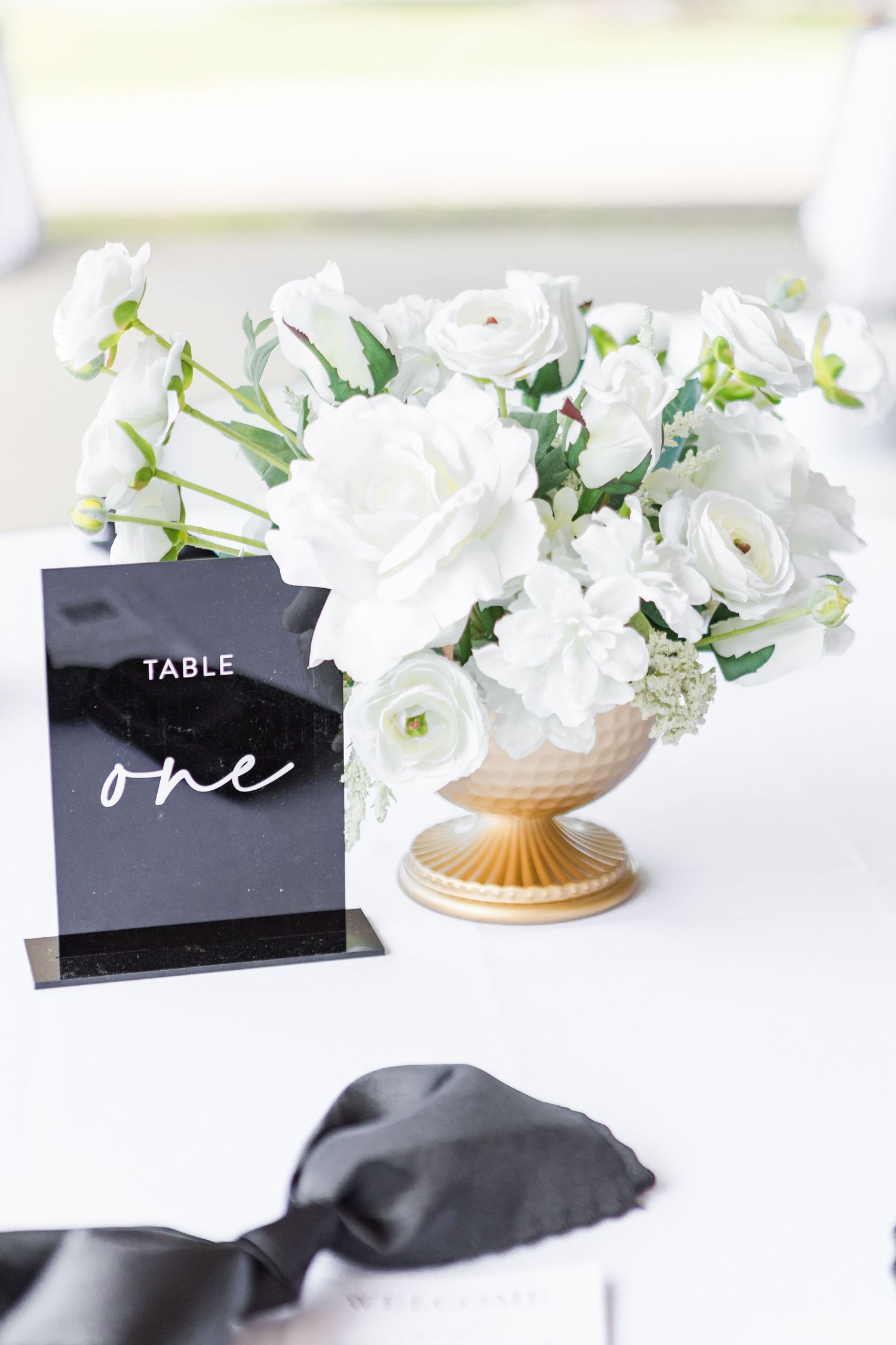 Black table number one sign with white roses in gold vase centerpiece.