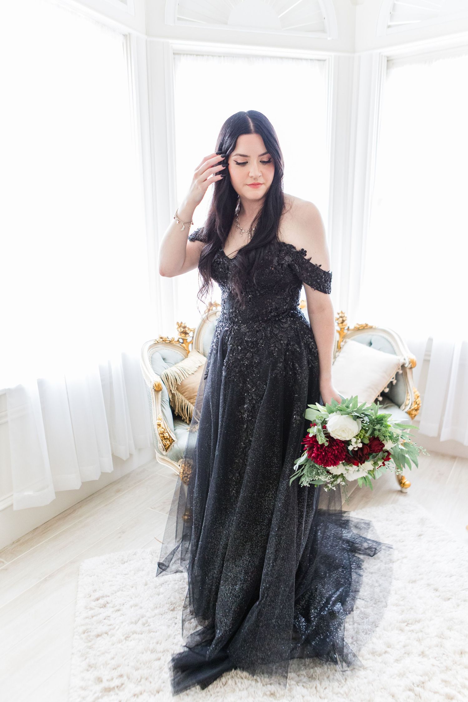 Elegant black lace dress photographed in a bright white studio with gold accents and floral details.