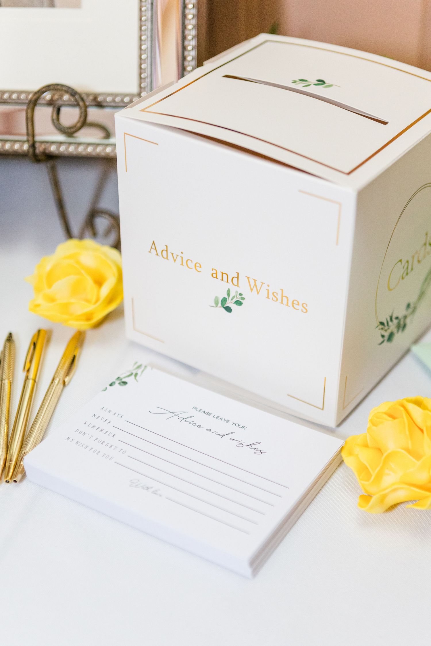 White wedding advice and wishes boxes decorated with gold text and floral accents.