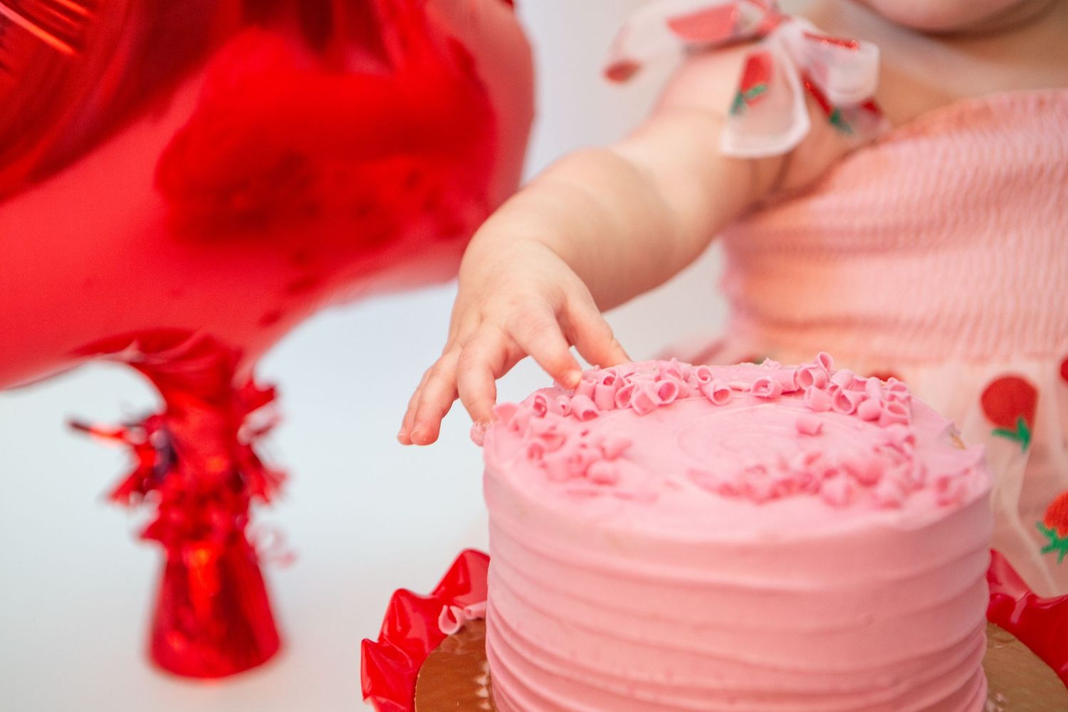 Pink frosted cupcake with red decorations being prepared in a step by step process.