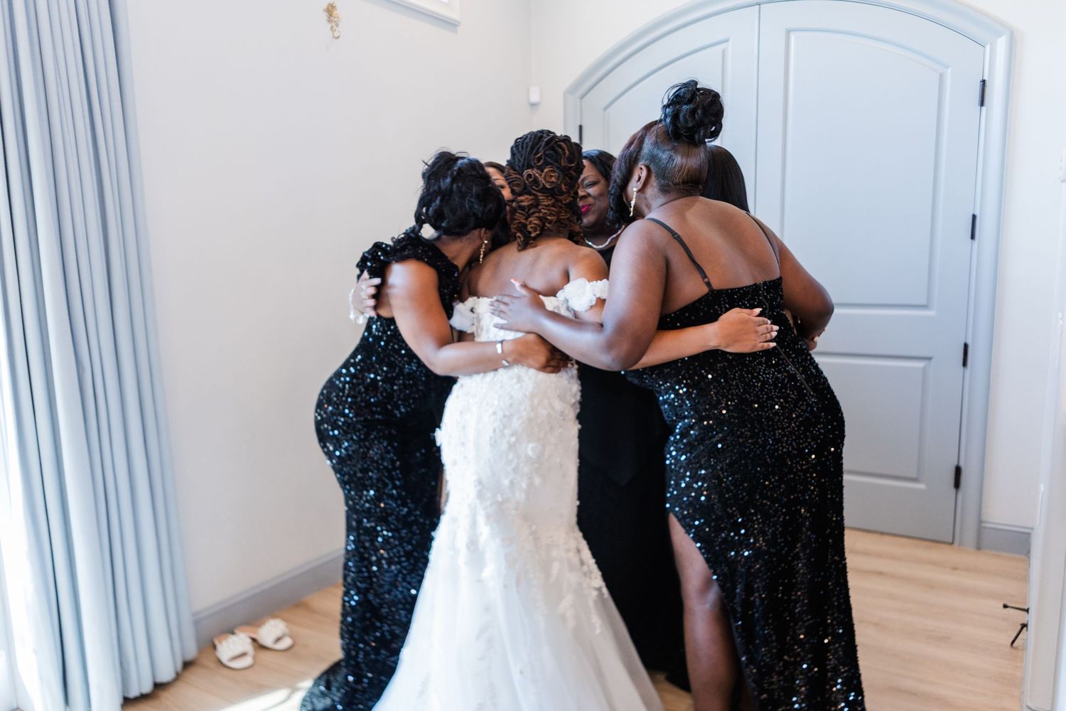 Wedding preparation scene showing white curtains and dresses in a bright room.