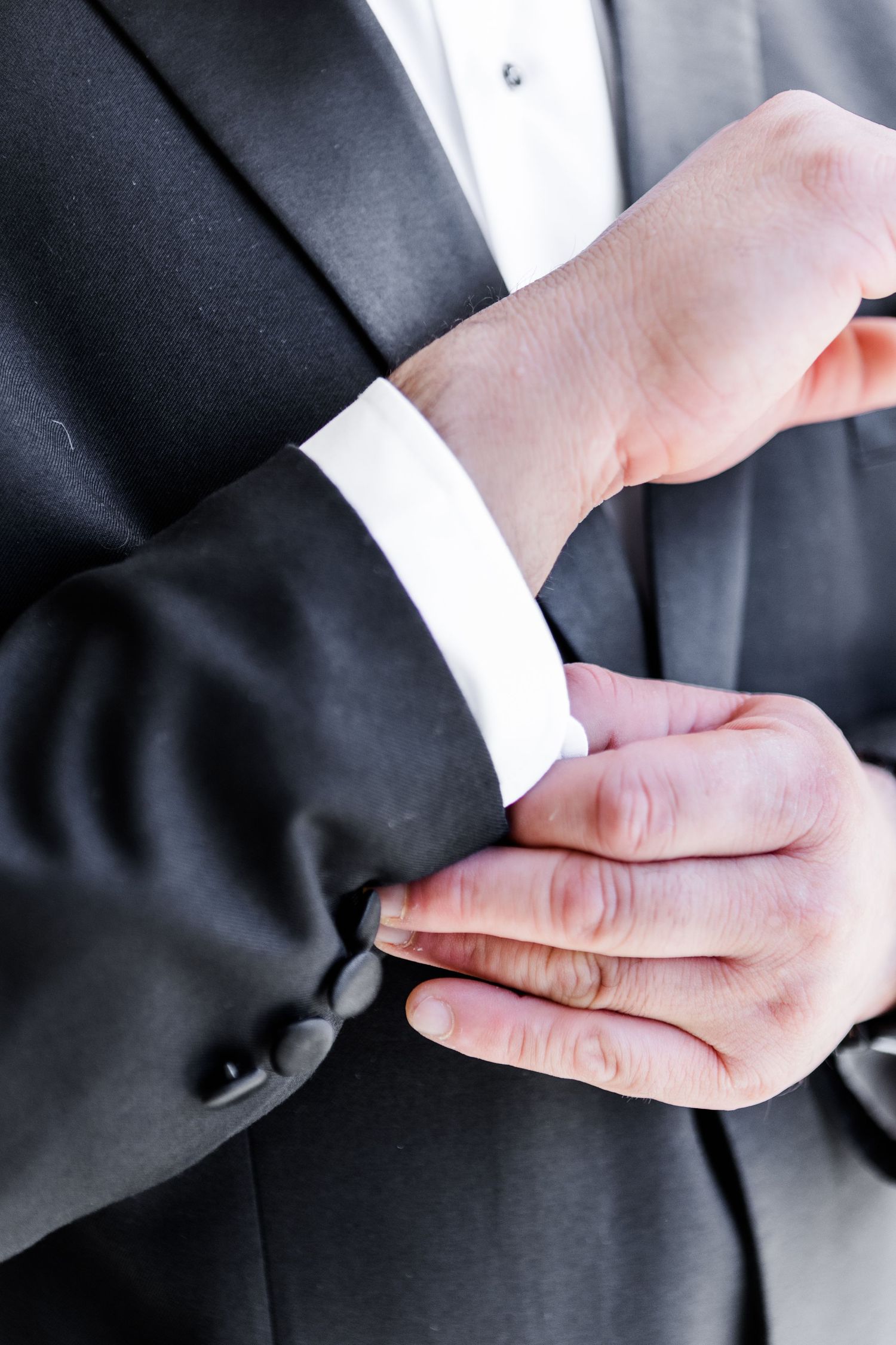 Series of hands adjusting formal suit cuffs and sleeves.