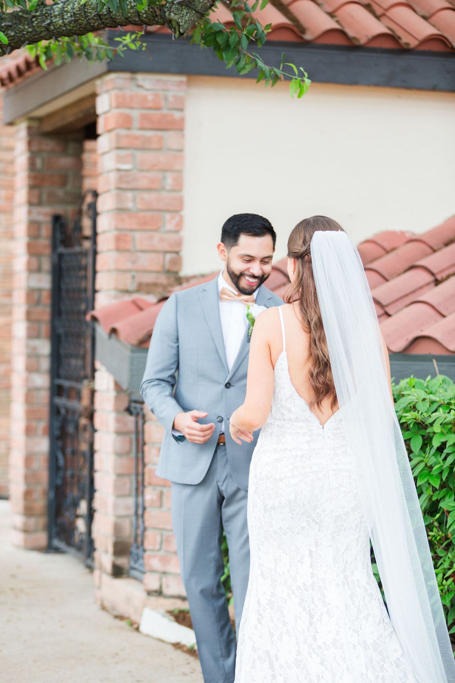 Joyful wedding couple sharing a moment together outside a Spanish-style building.