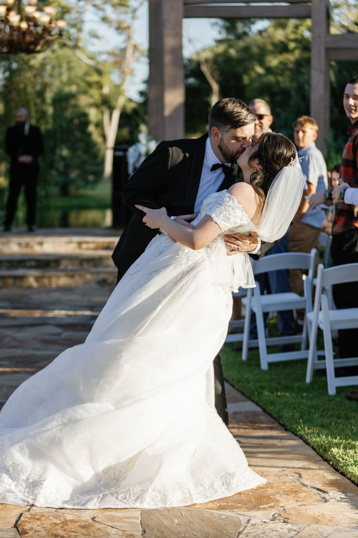 Wedding couple shares playful moments on stone patio during outdoor ceremony.