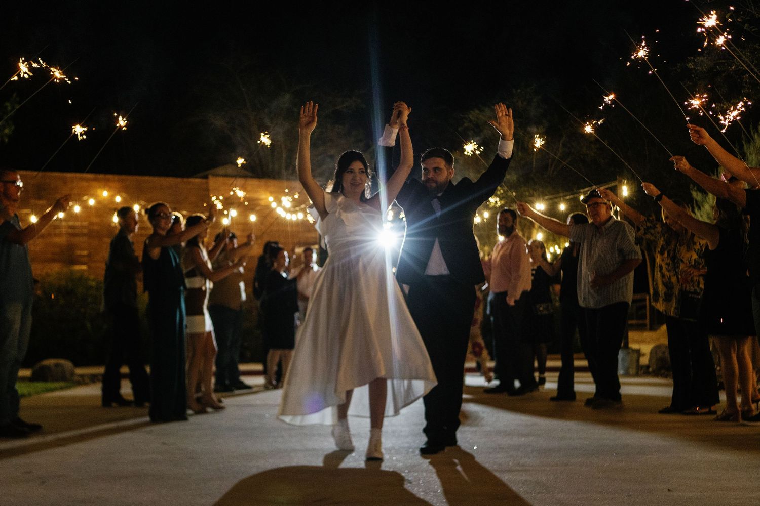 Wedding sparkler exit with guests creating magical light tunnel for celebration.