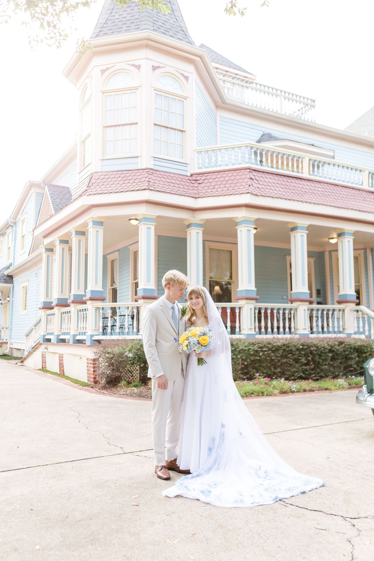 Elegant Victorian house with wrap-around porch serves as wedding venue backdrop.