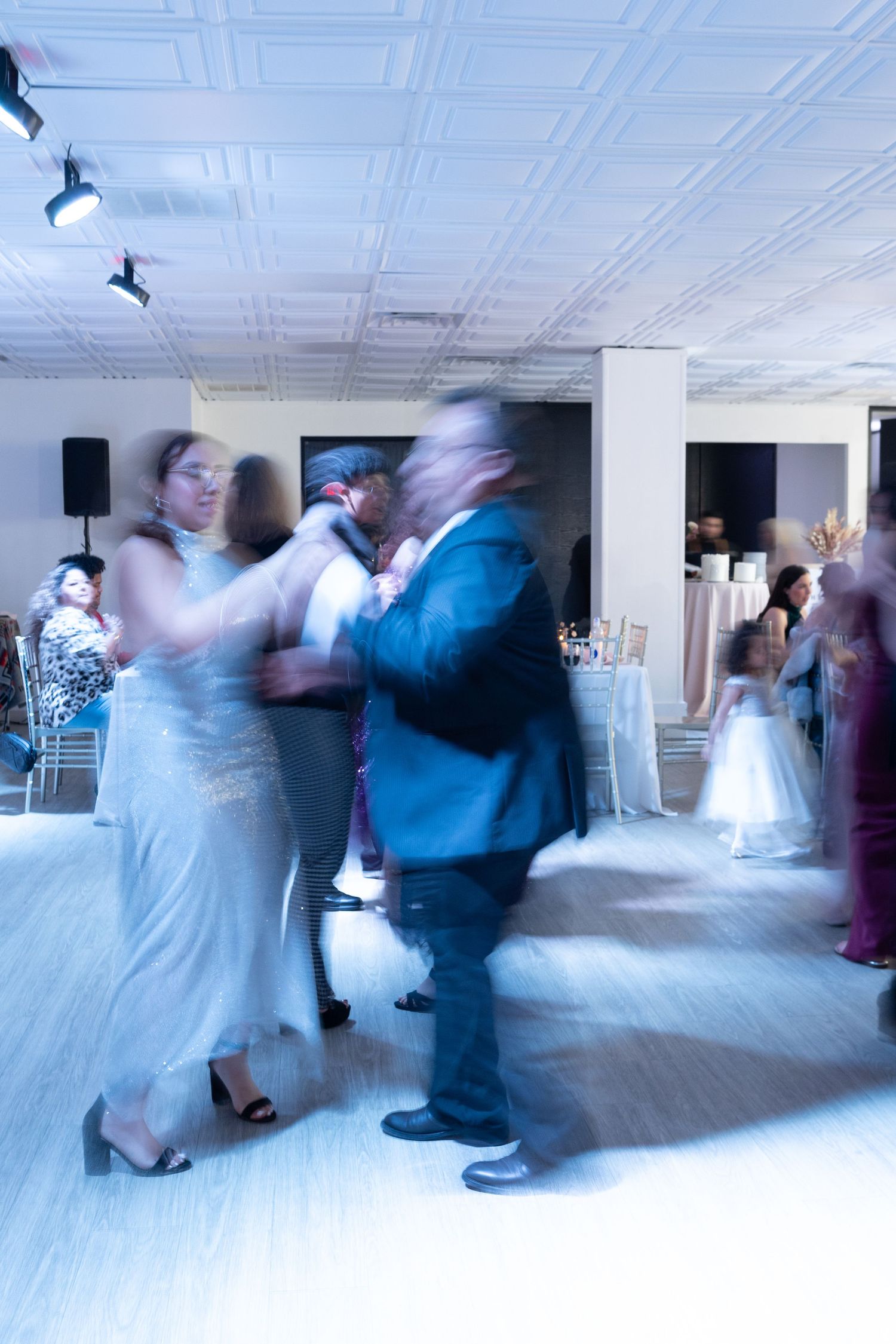 Couples dancing in formal attire at a reception with motion blur effect.