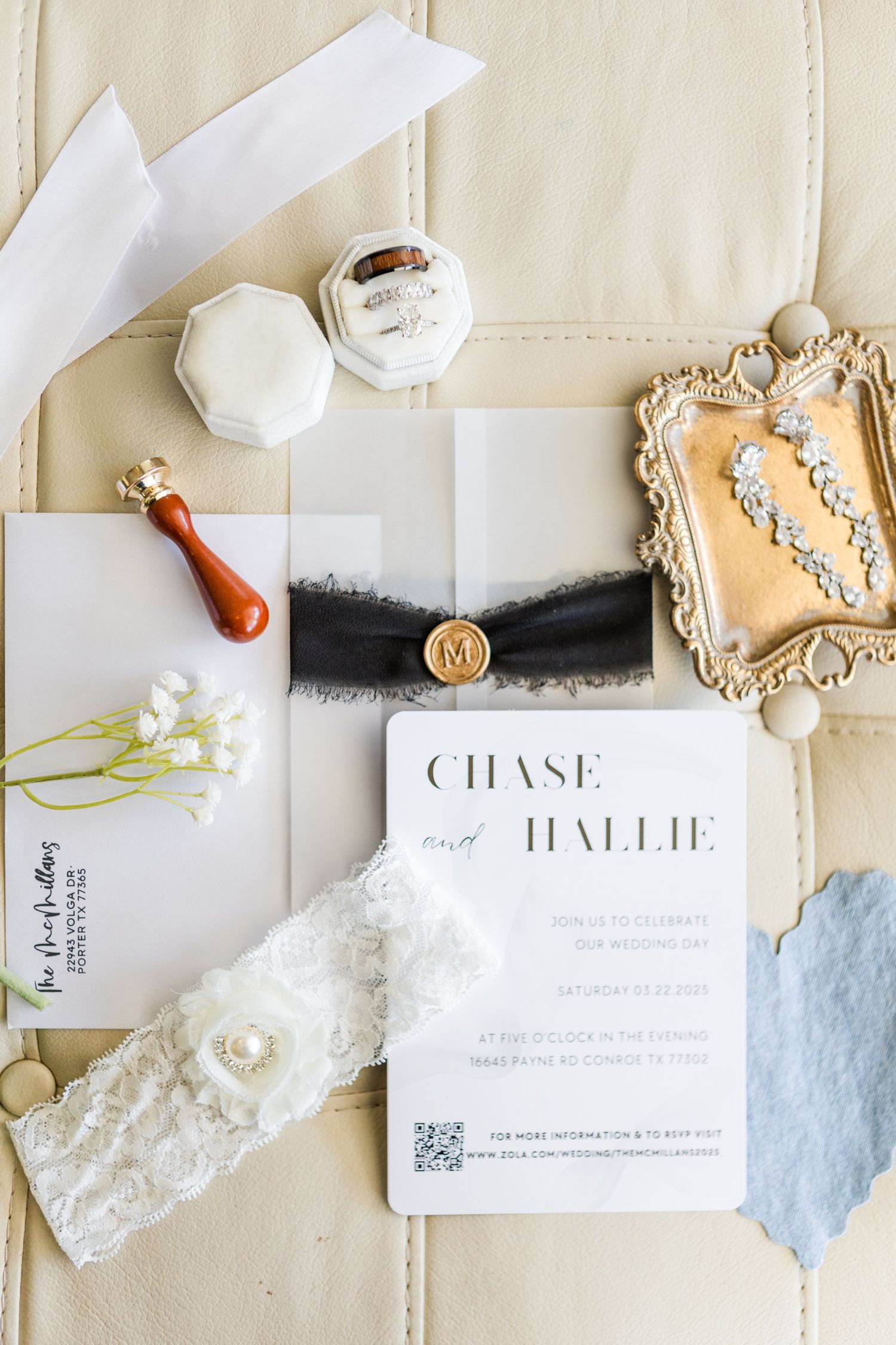 Elegant wedding stationery with wax seals and vintage lace details arranged on a cream tufted surface.
