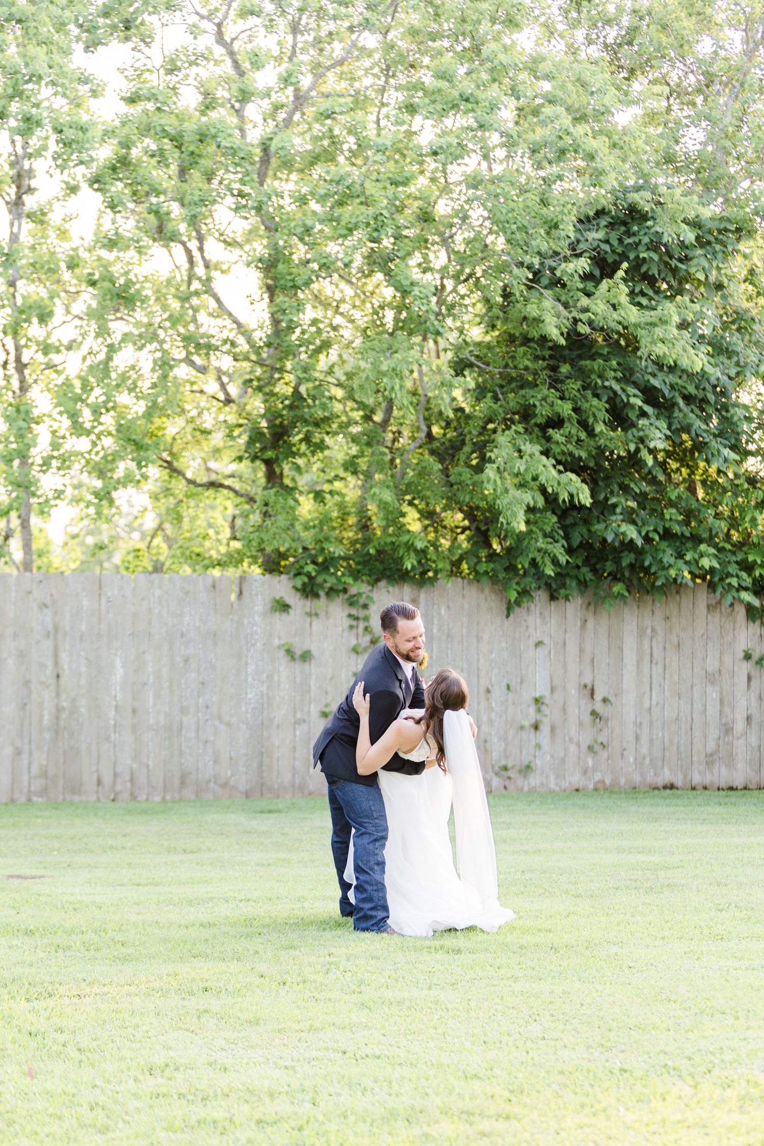 A romantic moment captured in a backyard garden setting with trees in the background.