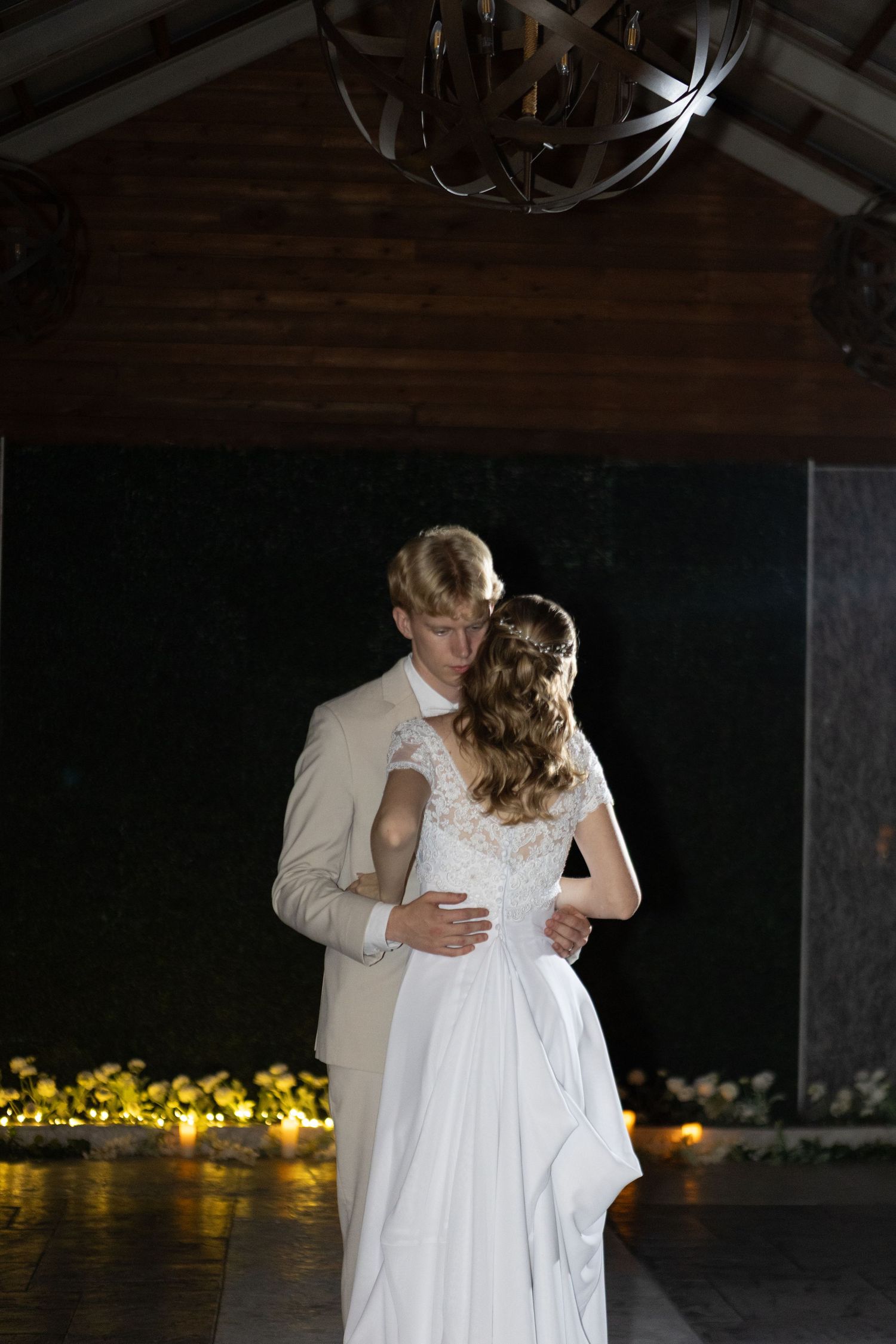 Wedding couple sharing a romantic first dance in a dimly lit venue with string lights.