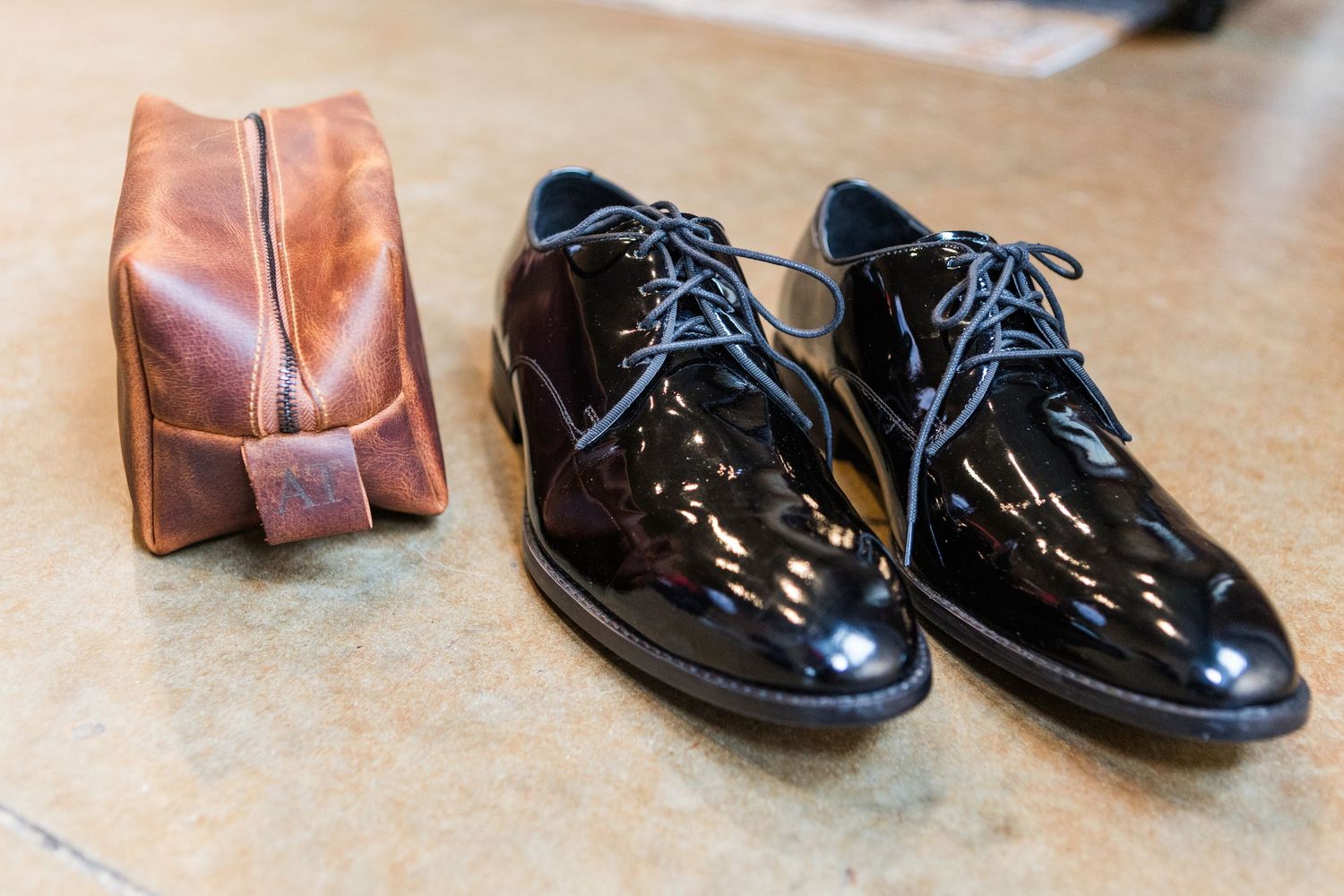 Polished black dress shoes arranged in a row on a wooden floor.