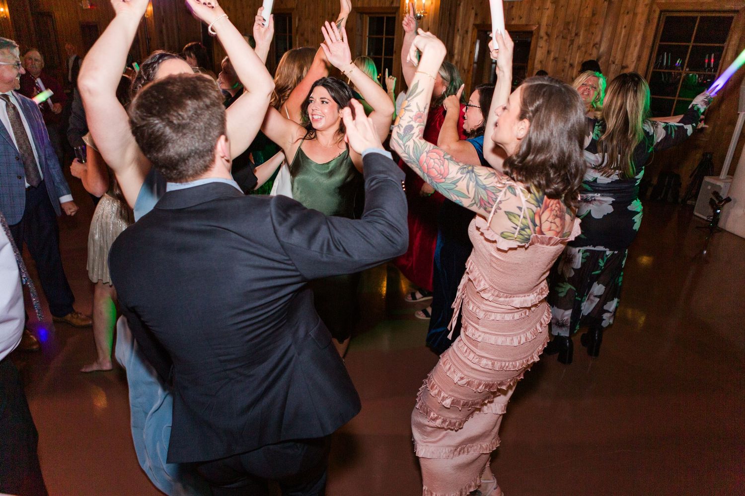 Guests dancing and celebrating at a dimly lit wedding reception venue.