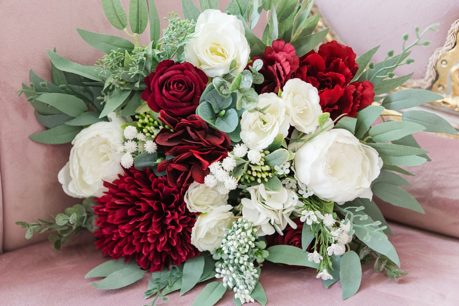 Beautiful floral arrangement featuring deep red and white roses with eucalyptus leaves.