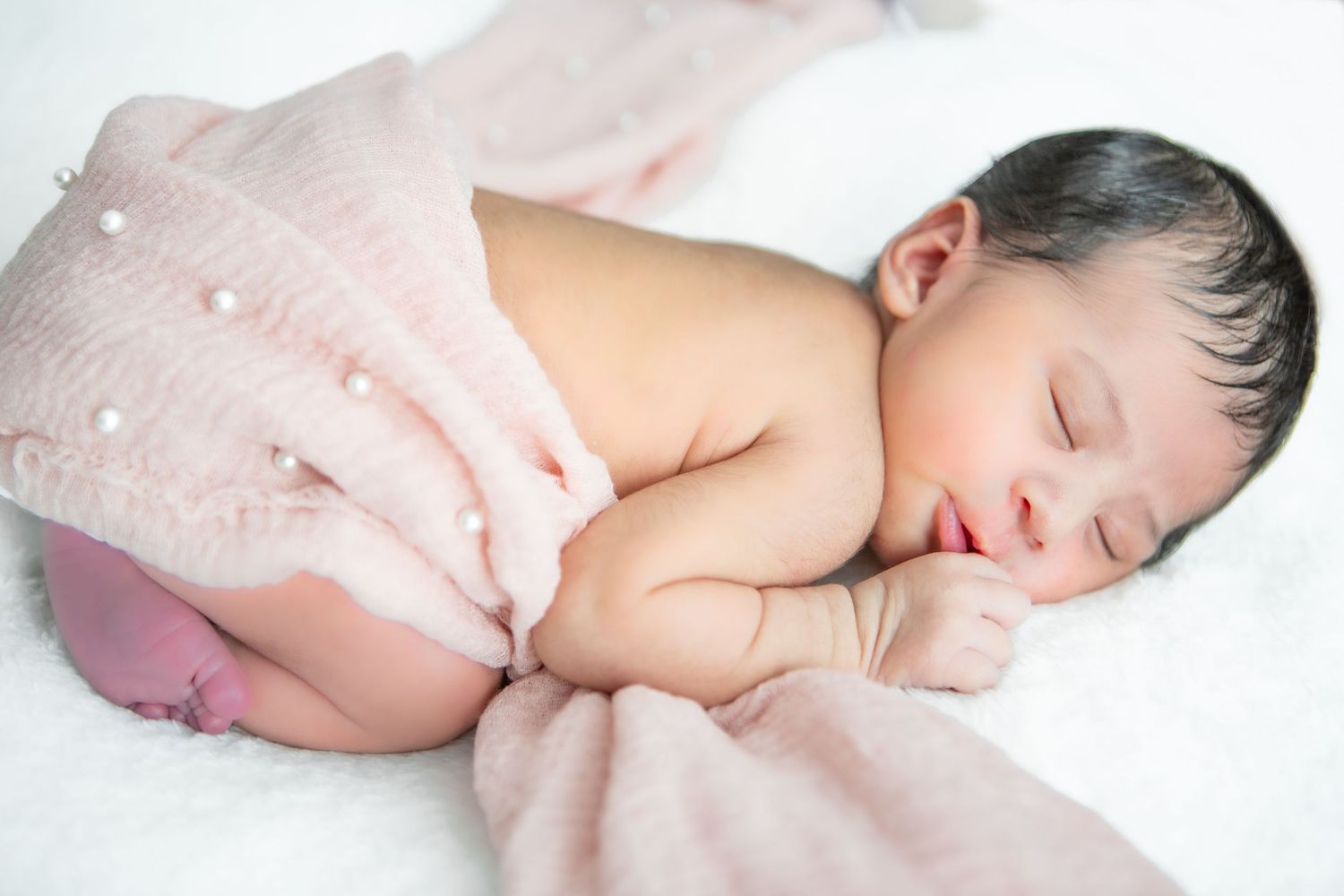 Artistic newborn photography series featuring soft pink tones and gentle poses.