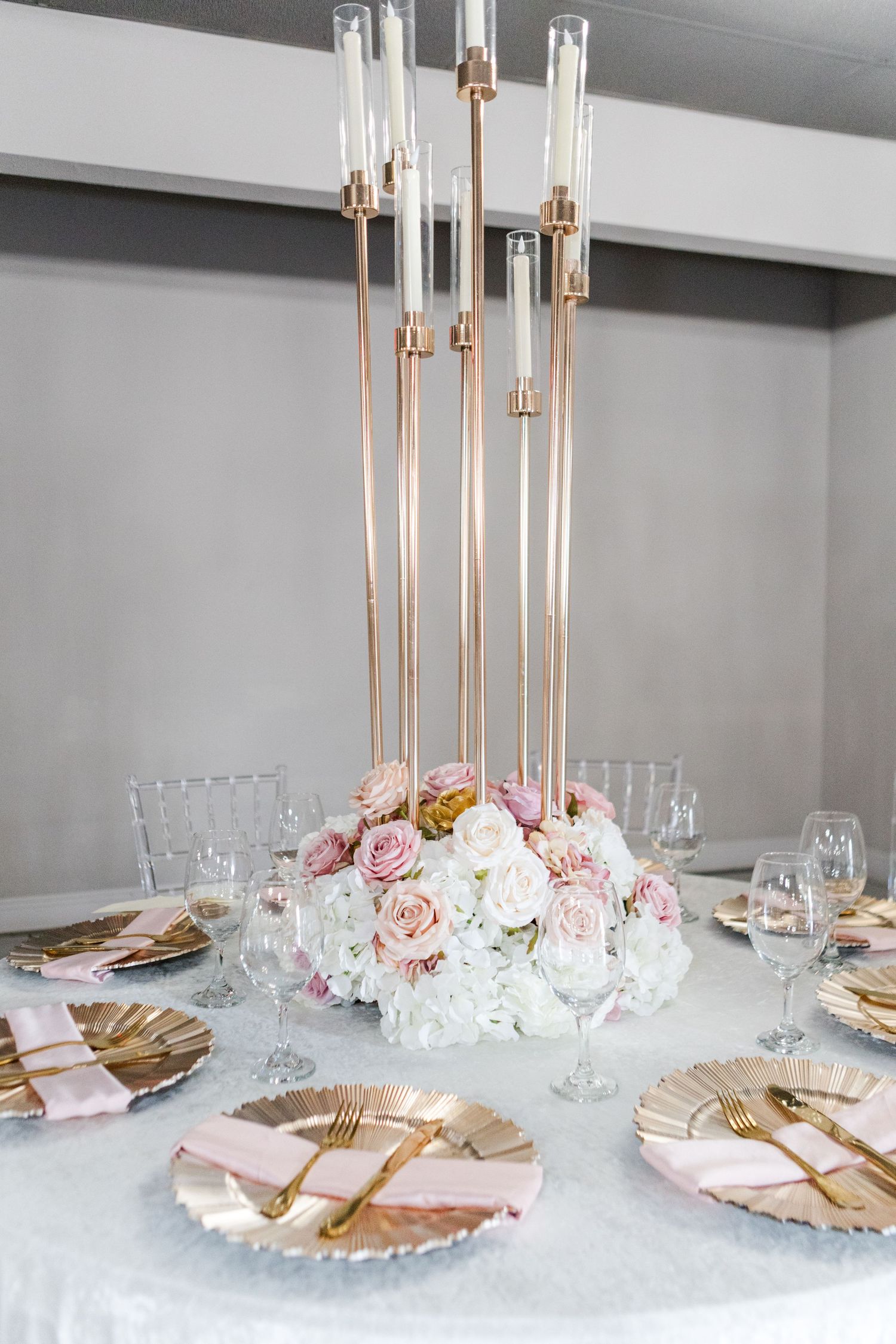 Luxurious table setting with tall gold candlesticks and crystal glassware on white tablecloth.