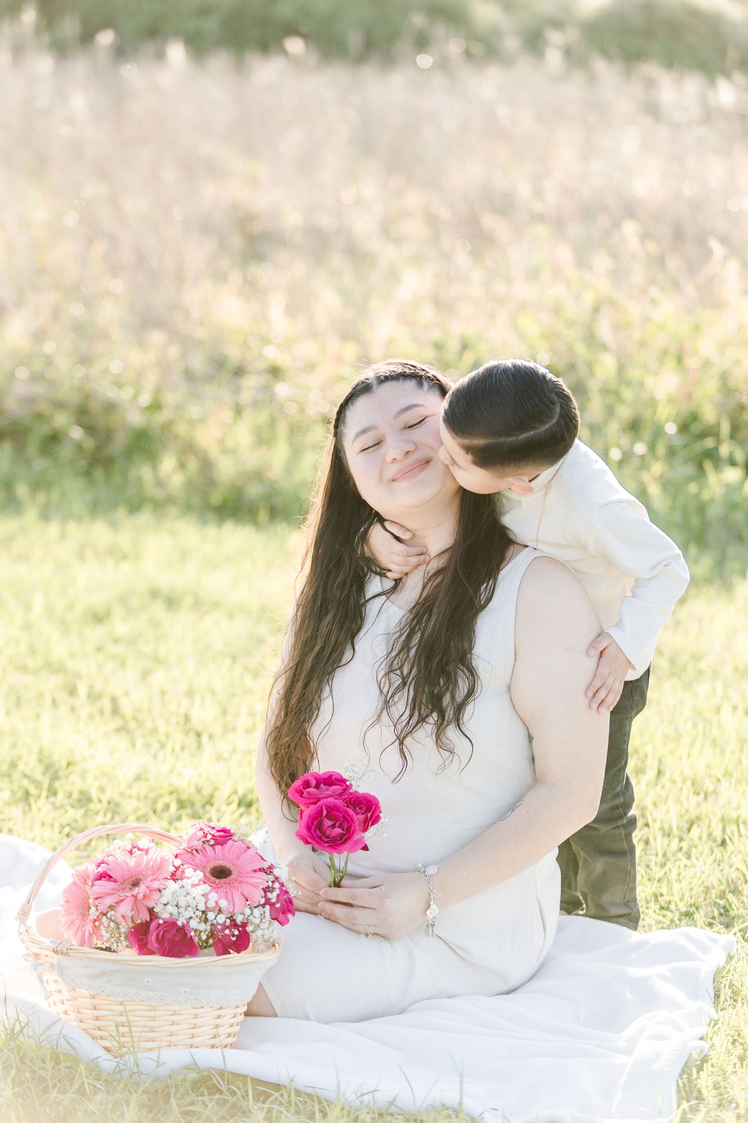 Intimate family moments captured on blanket with pink flowers in golden sunlight.