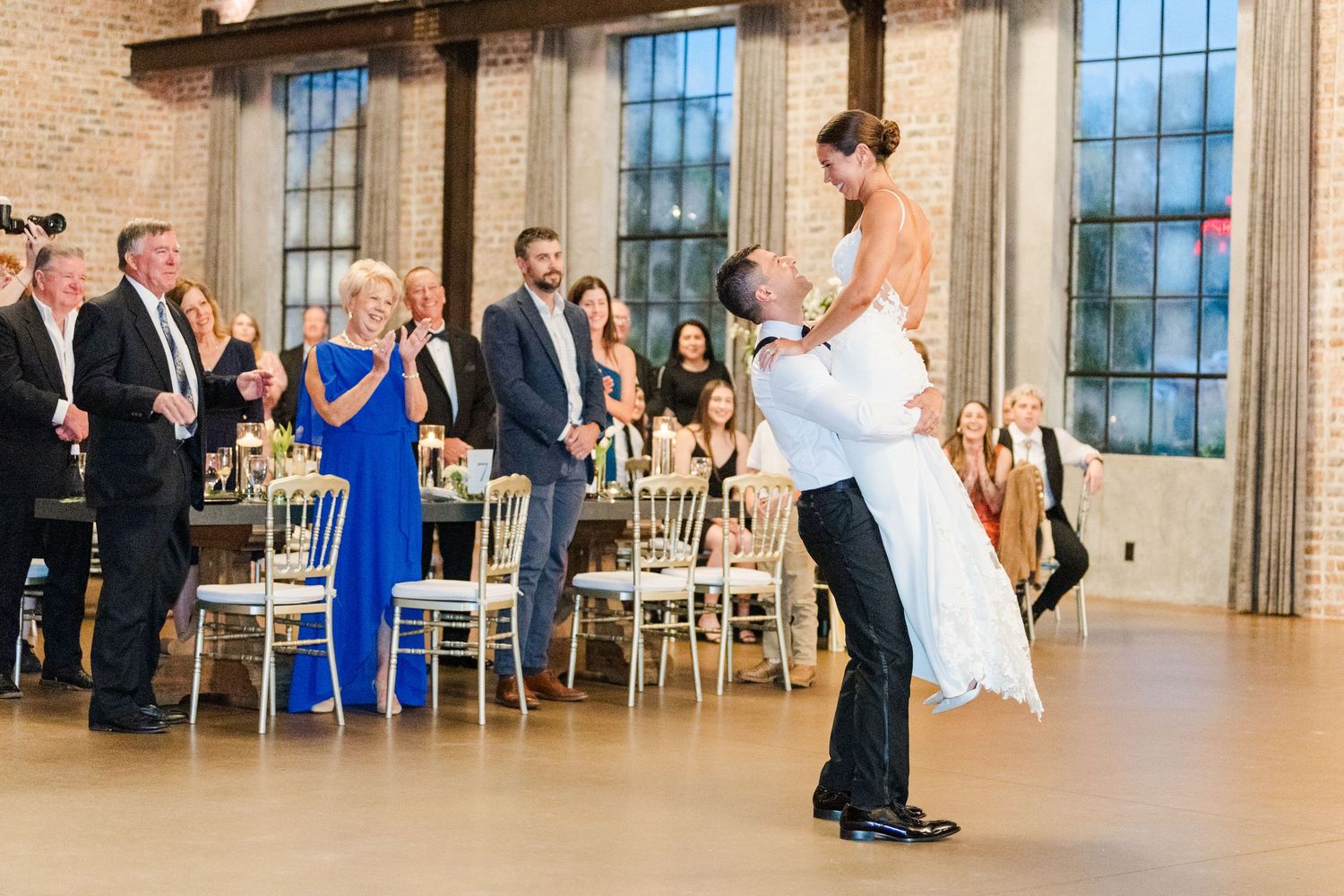 Panoramic view of a wedding reception showing couples dancing in an elegant brick venue.